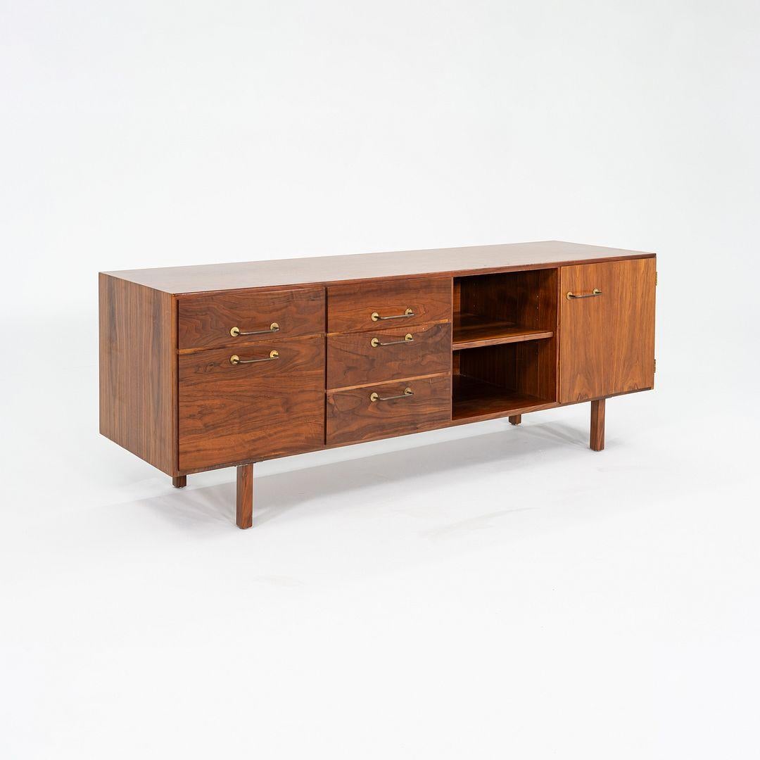 This is a walnut credenza / cabinet designed by Jens Risom and produced by his company, Jens Risom Design. This particular piece was handcrafted in the USA and dates back to the 1970s. The credenza has a beautifully grained walnut case, with several