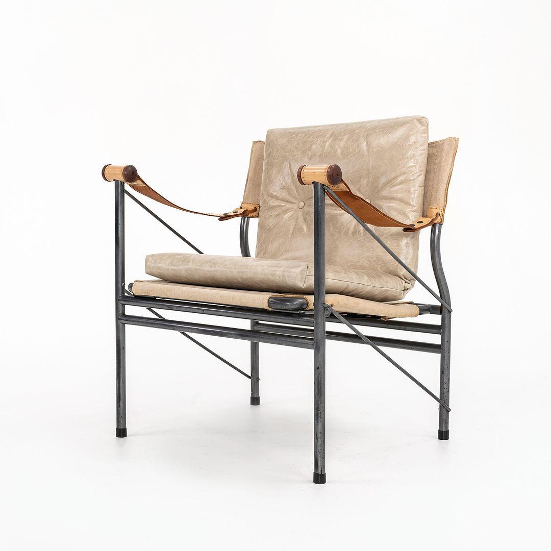 Se trata de una tumbona Safari plegable Colombo, modelo 907, diseñada (creemos) por Joe Colombo. La silla tiene el asiento y el respaldo de lona de lino, y los brazos de piel vachetta en tono natural. En uno de los brazos está grabado Colombo 907.