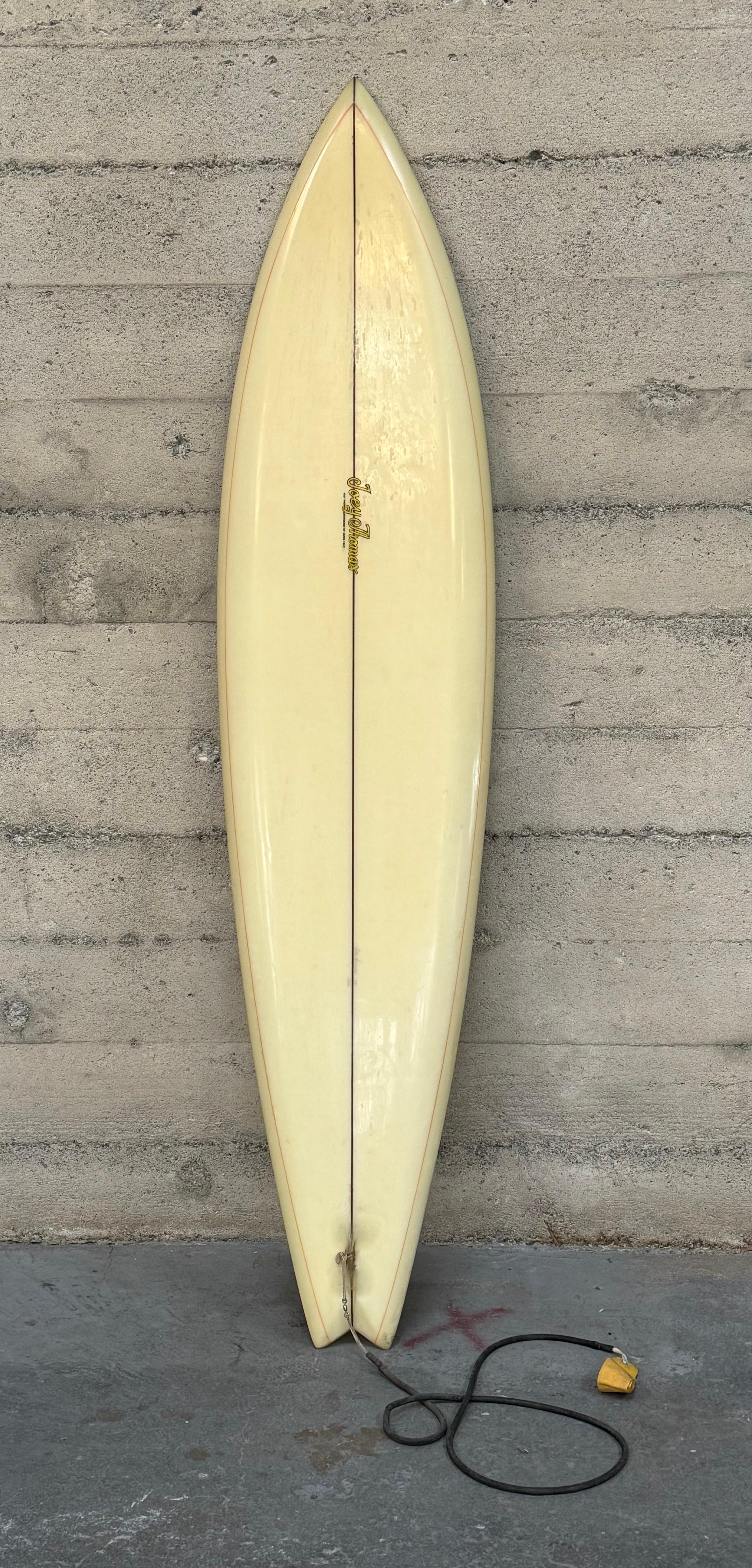 1970s era surfboard by Santa Cruz shaper / surfer Joey Thomas, this example has a single foiled wooden fin, swallow tail, beak nose, down rail with a resin pin line along the rails configuration which was a popular shape by the influences from what