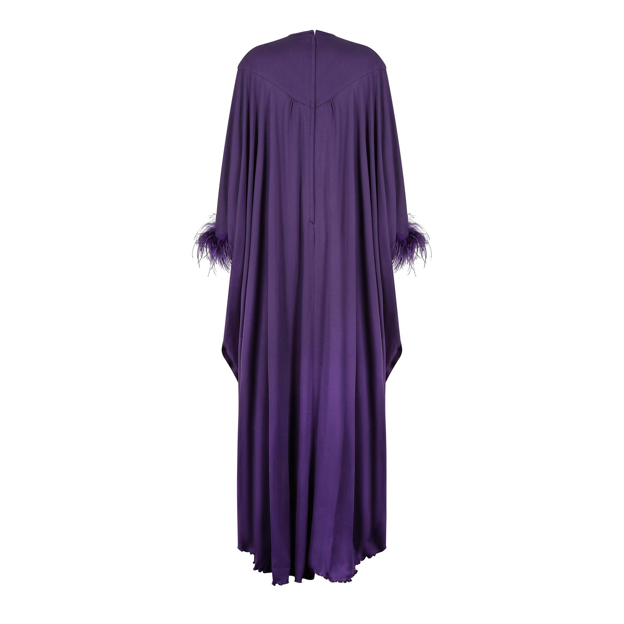 This is a very striking and good quality example of exuberant 1970s fashion from renowned occasion wear designer John Charles.  In a glorious shade of deep purple the dress has a deep yoke and high neck design with an oversized and wonderful trapeze