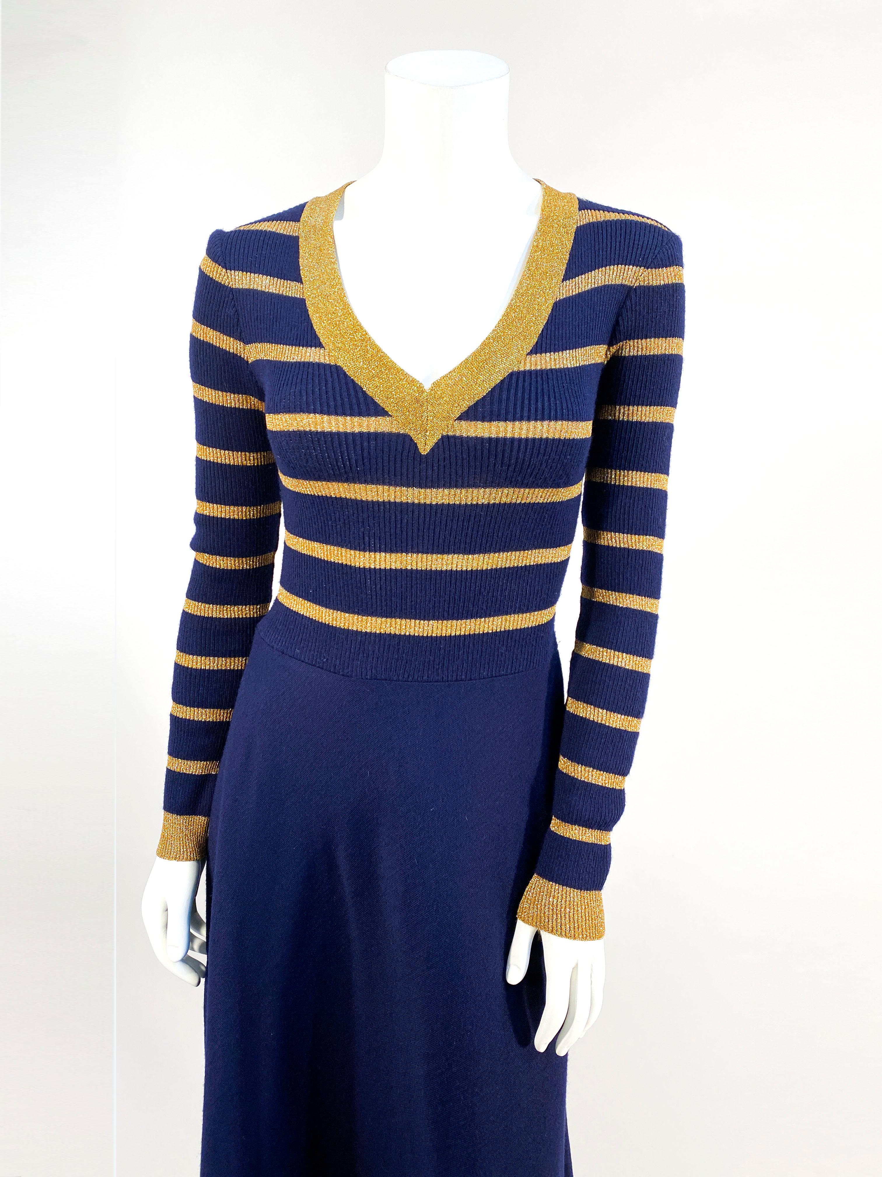 1970s Joseph Magnin navy blue and gold metallic knit wool and acrylic blend dress with a v-neck boarded in gold. The skirt is full-length with a boarder along the bottom. The long sleeves have a ribbed gathered cuff.