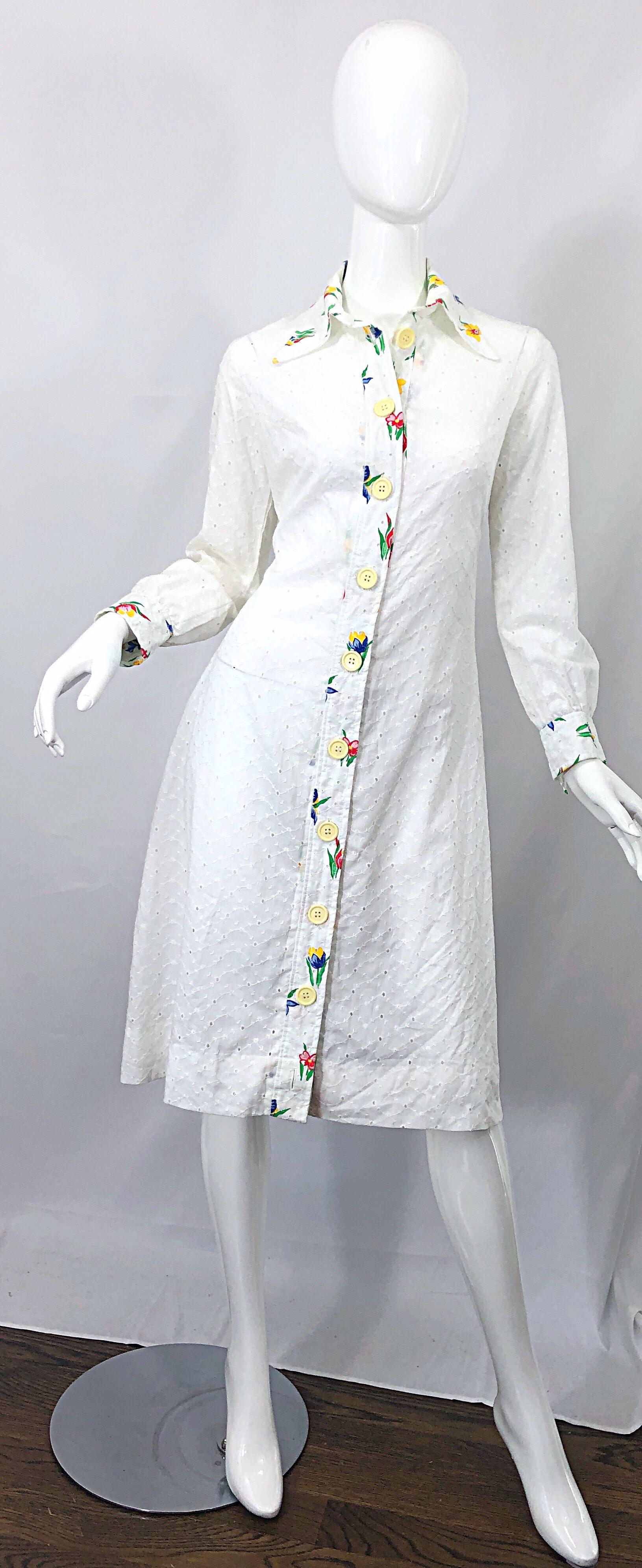 Chic 1970s JOSEPH MAGNIN white cotton eyelet embrodiered long sleeve shirt dress! Features a stark white color with embroidered flowers down the front center, collar, and sleeve cuffs. Vibrant colors of red, blue, yellow, green and orange. Buttons