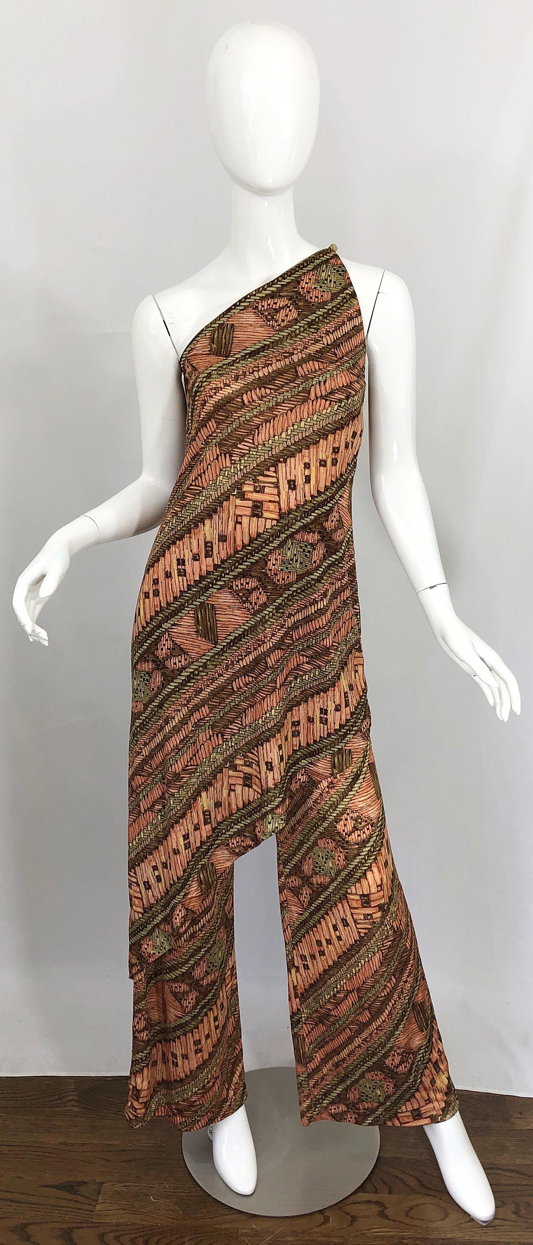 Incredible mid 70s vintage JOY STEVENS batik print one shoulder asymmetrical hem tunic dress and wide leg trousers ensemble! Features warm colors of brown, peach, and ivory throughout. Tunic features an asymmetrical hem with button closure at top