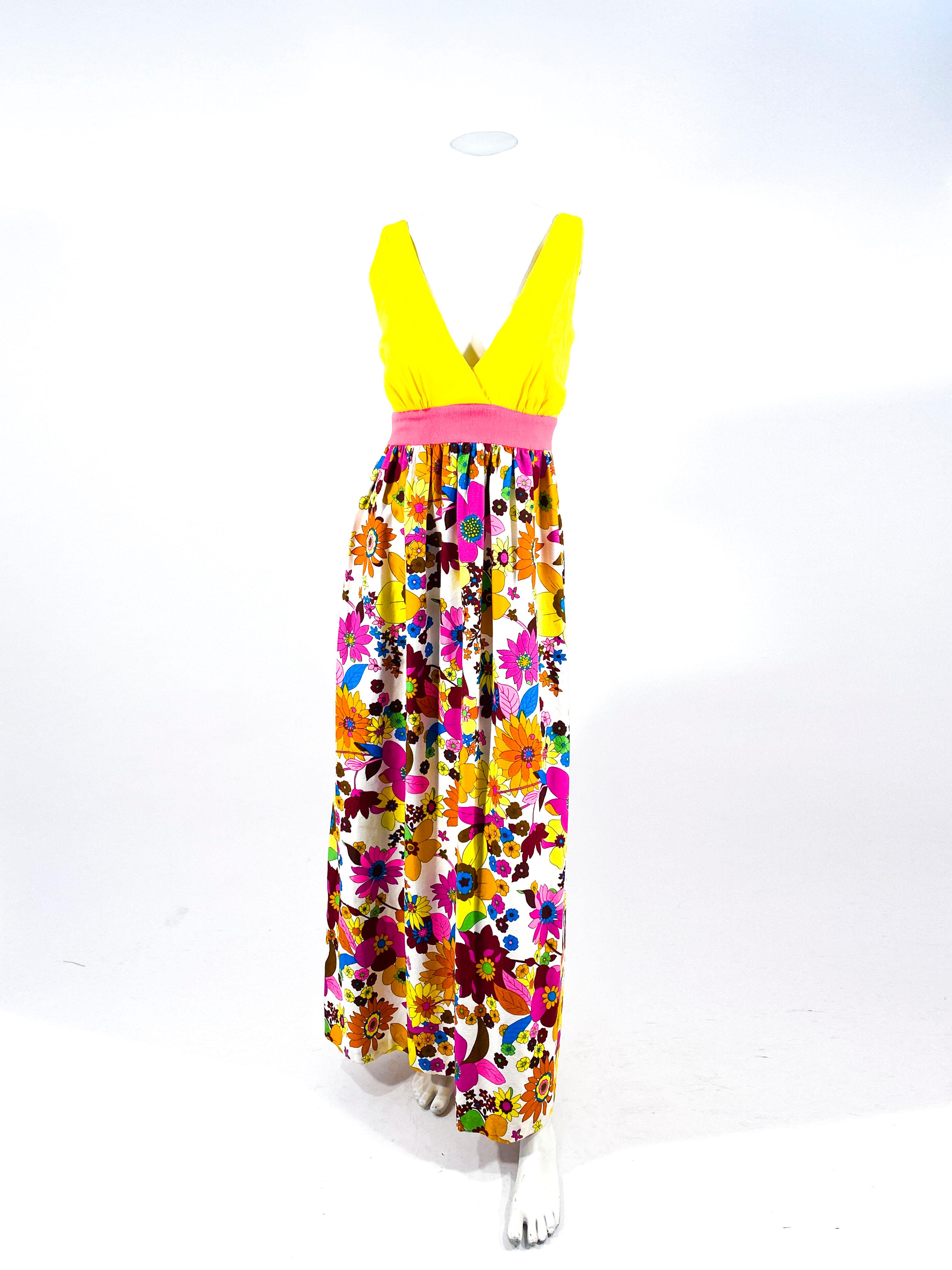 1970s Kamehameha label Hawaiian floral printed bark cloth maxi day dress featuring vibrant tones of magenta, rust, blue green, and yellow. The bight yellow faux wrap bodice is complementary to the hot pink applied waistband and full printed skirt.