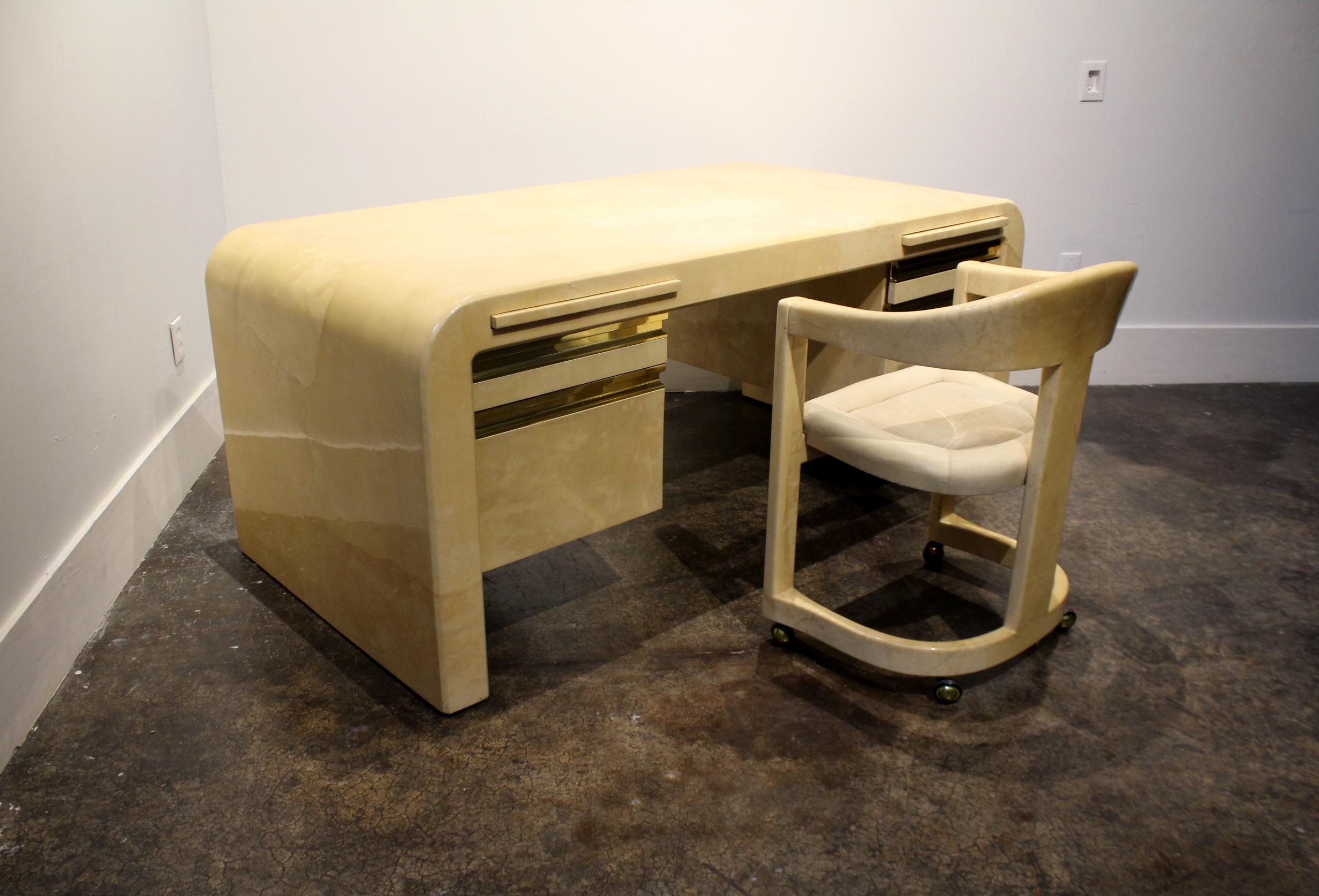 Large waterfall style desk designed and manufactured by Karl Springer in the 1970s. Whitish-tan, lacquered goatskin with gold pulls. Desk has two small top drawers, two large bottom drawers and two pull-out writing surfaces over the drawers. Comes