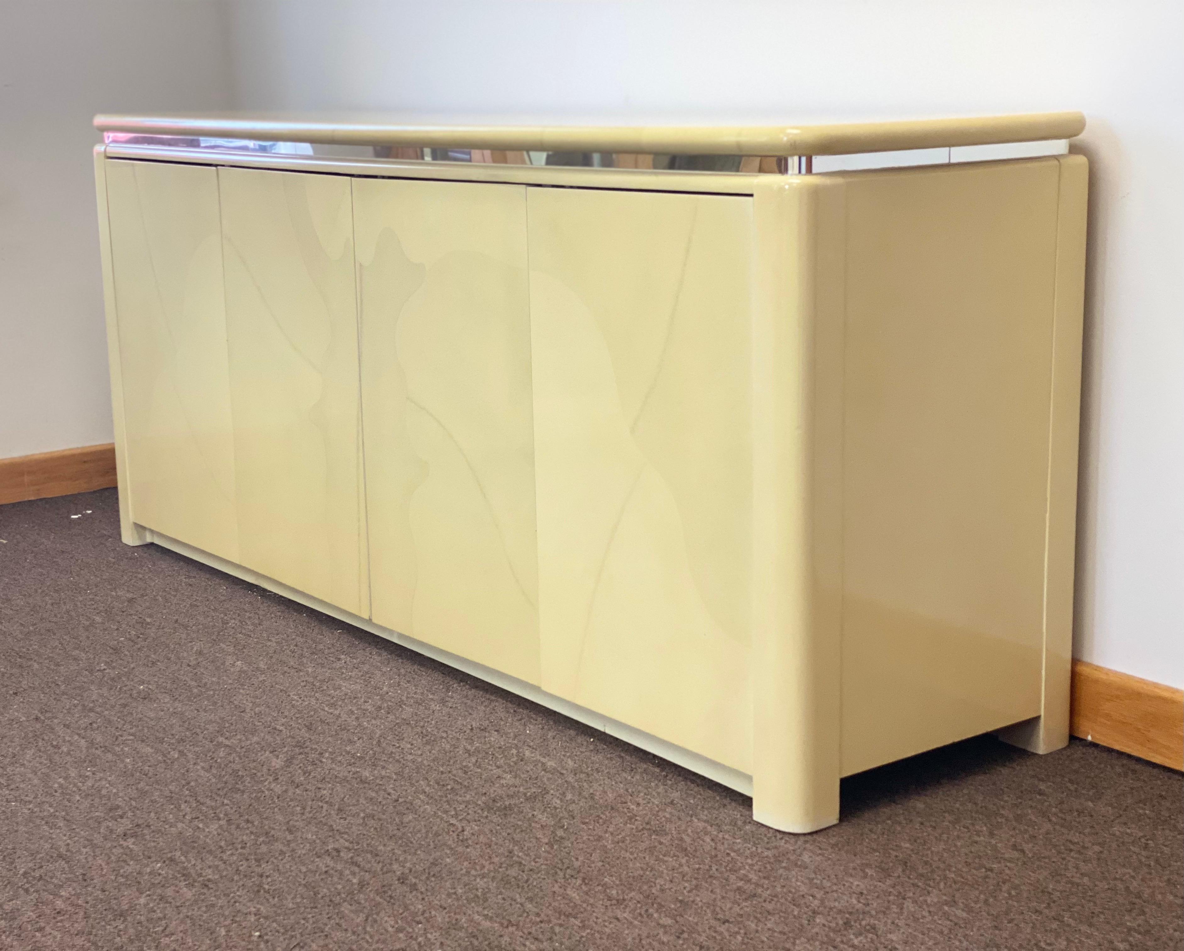 We are very pleased to offer a chic credenza in the style of Karl Springer, circa the 1970s. This six feet long sideboard showcases a lacquered goatskin finish with a chrome banding trim. The spacious interior provides plenty of versatile storage.