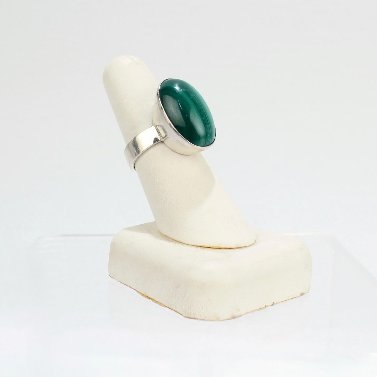 A great 1970s Kaunis Korn modernist ring in sterling silver set with a large malachite cabachon. 

The shank stamped PH for the silversmith (possibly Paul Henningsen), Y7 for 1976, 925, and with the KAUNIS KORU mark.

Ring size: ca. 7 3/4 

Items