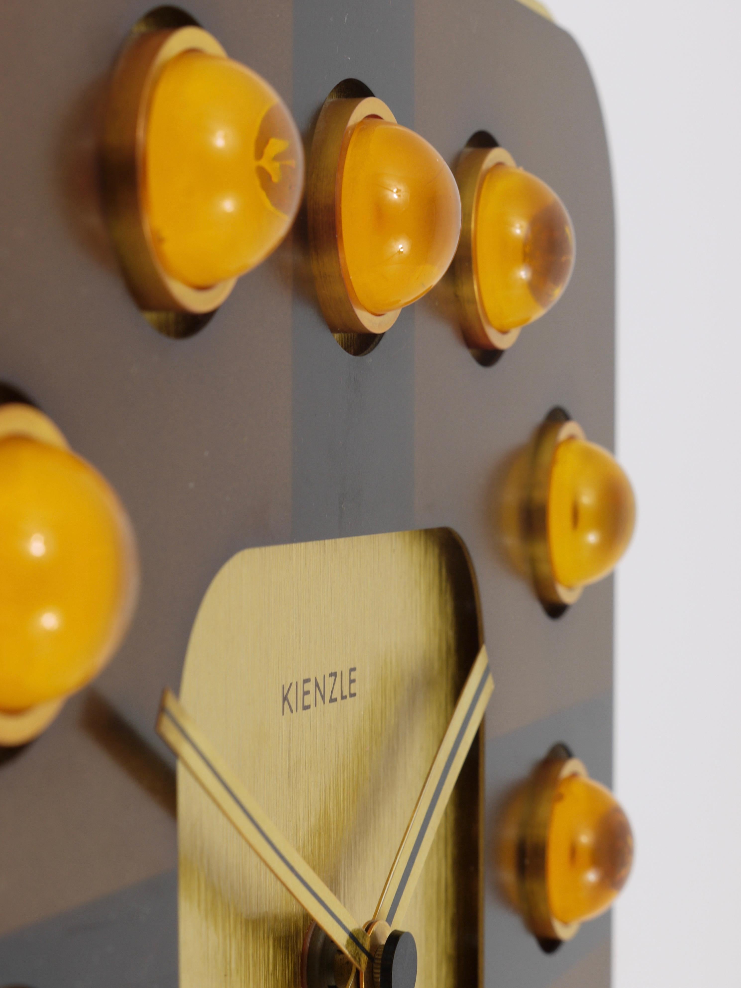 Eine schöne quadratische 1970er Hollywood Regency Wanduhr von Kienzle Deutschland. Die Uhr hat ein goldenes Gehäuse:: ein Zifferblatt aus braun eloxiertem Aluminium mit schönen halbkugelförmigen Indizes aus durchsichtigem orangefarbenem Acryl.