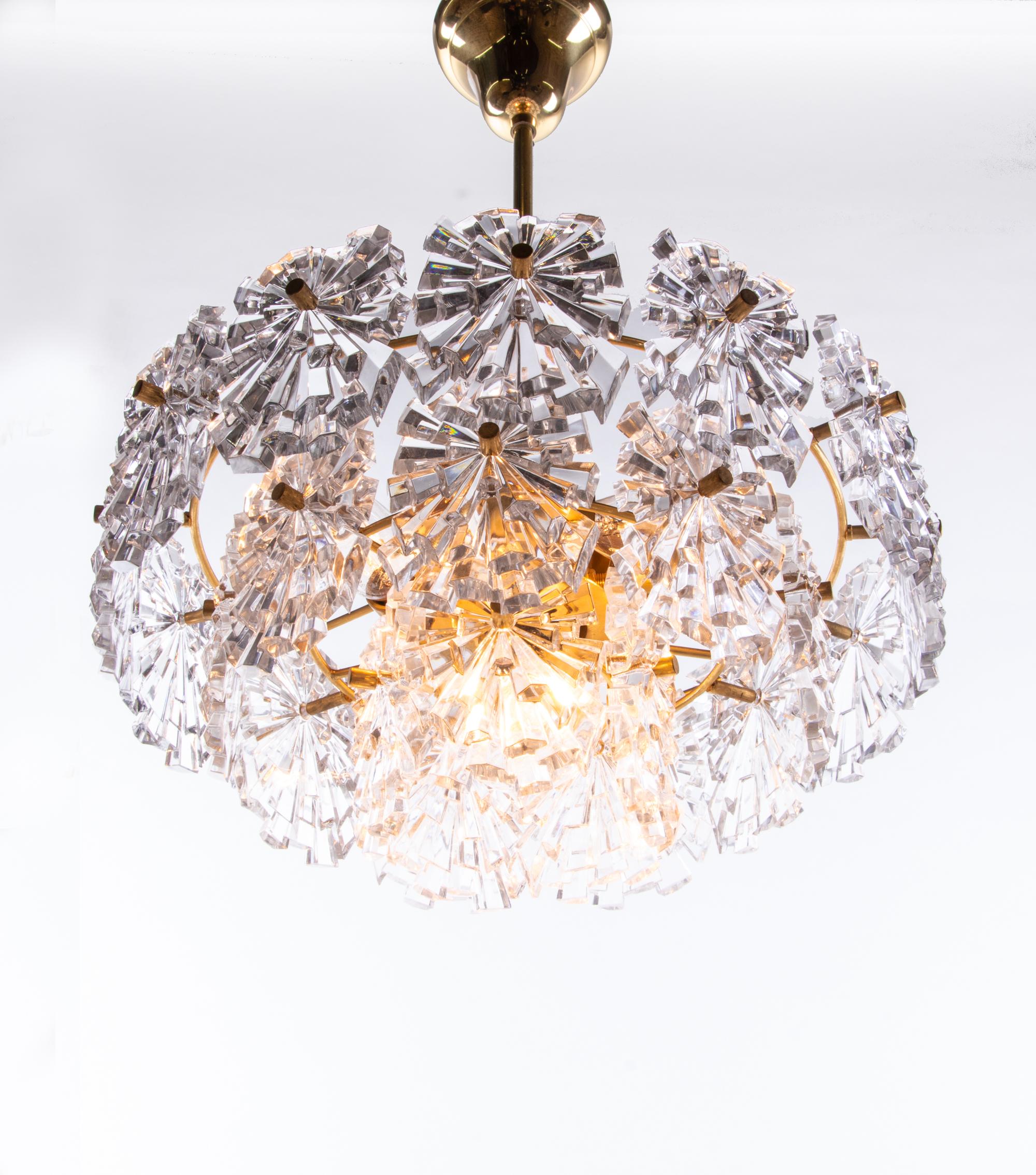Elegant starburst crystal glass chandelier with faceted crystals mounted on gold-plated brass frame. Star-shaped crystal glass resembles flowers. With this light you make a clear statement in your interior design. A real eyecatcher even unlit.