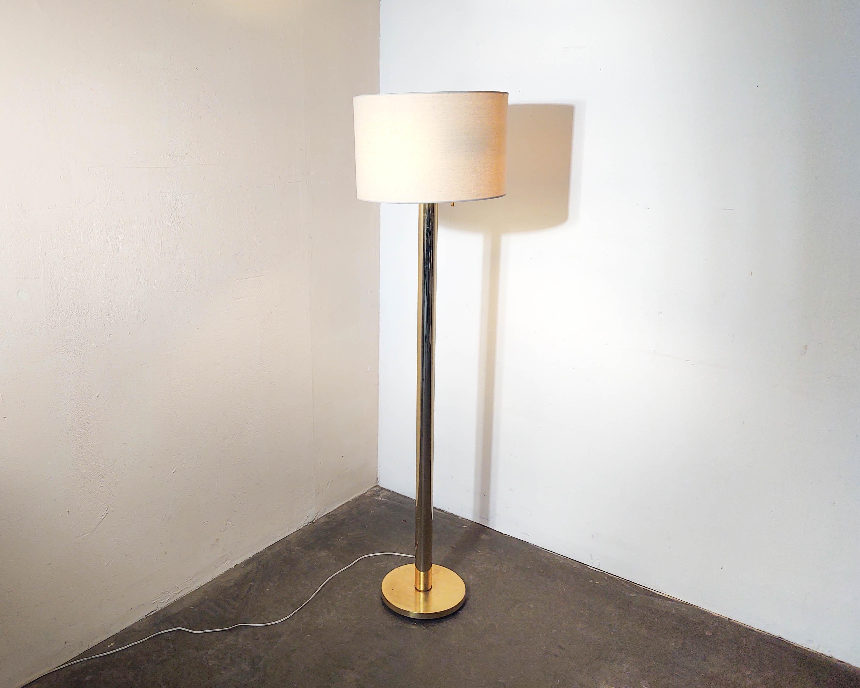Minimal brass column floor lamp with neutral woven drum shade by Koch + Lowy. Two lights with individual on/off pull chains. Overall great condition, some very light wear consistent with vintage age, interior shade lining has some cracking (hardly