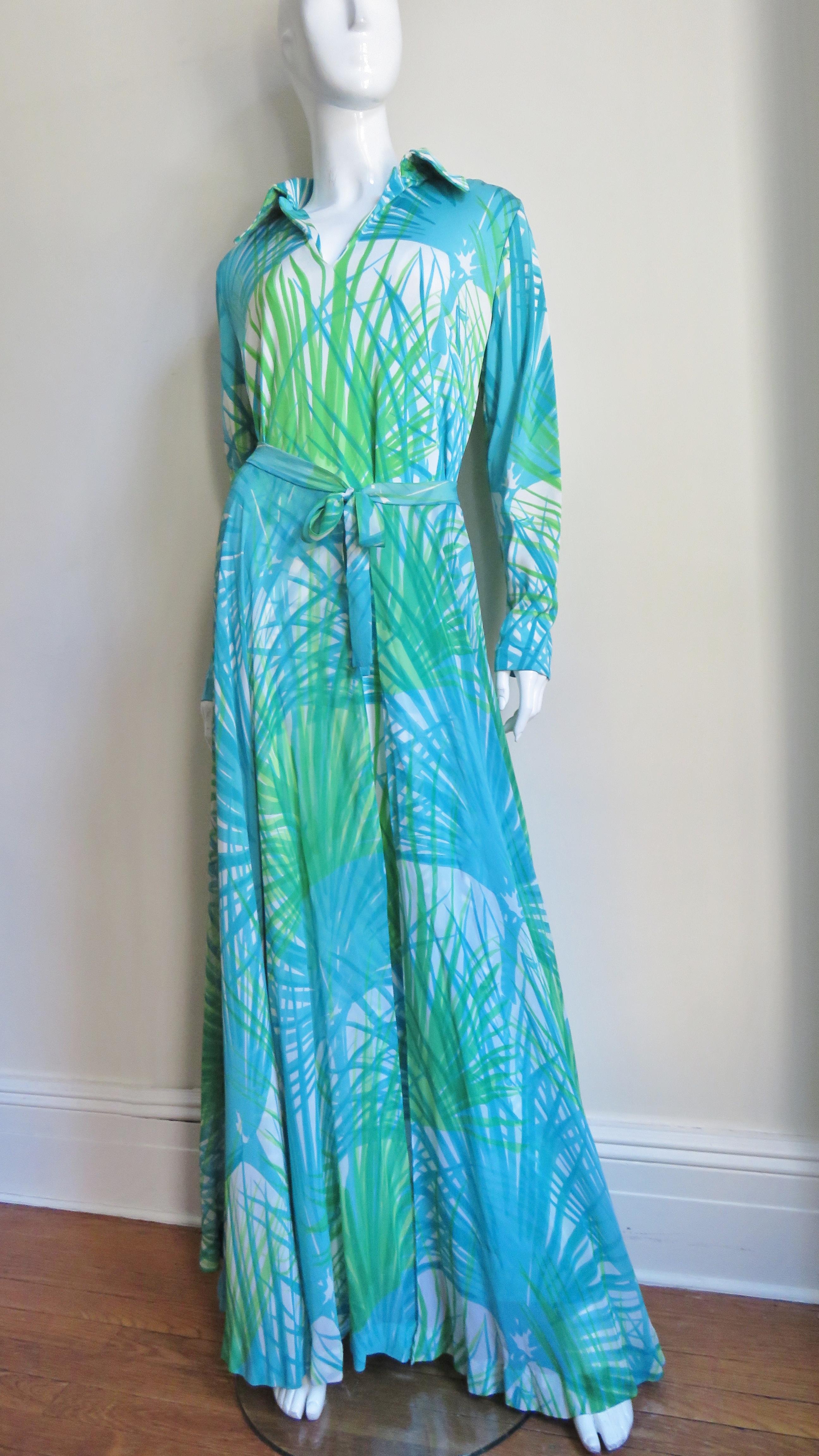A fabulous three piece jersey and silk set in a blue and green abstract fern print from La Mendola consisting of a maxi dress, tie belt and matching semi sheer silk over skirt. The dress has a collar V neckline, 5 self covered buttons at the wrists