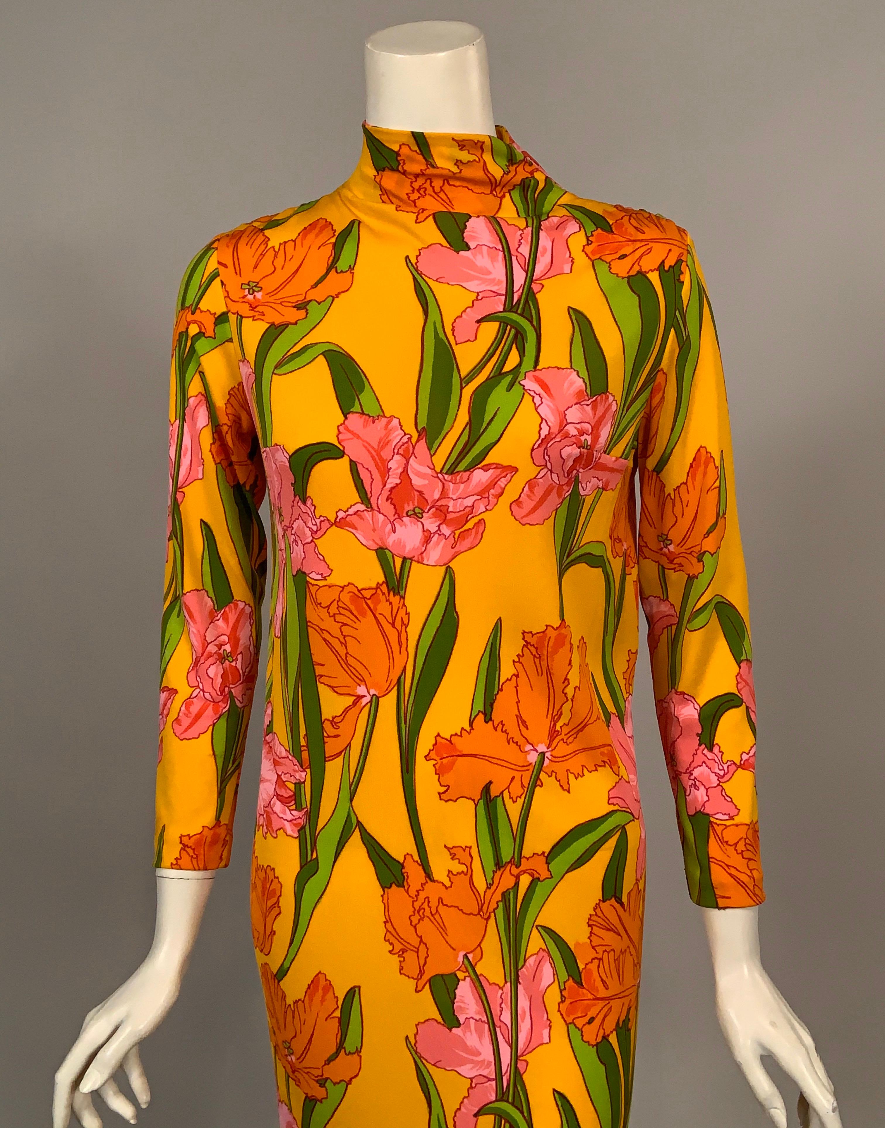 La Mendola has given us a bright and cheerful design of pink and orange Parrot Tulips with Spring green stems is striking against a sunny yellow background. The dress is made from silk jersey a high neckline, long sleeves a matching tie belt and