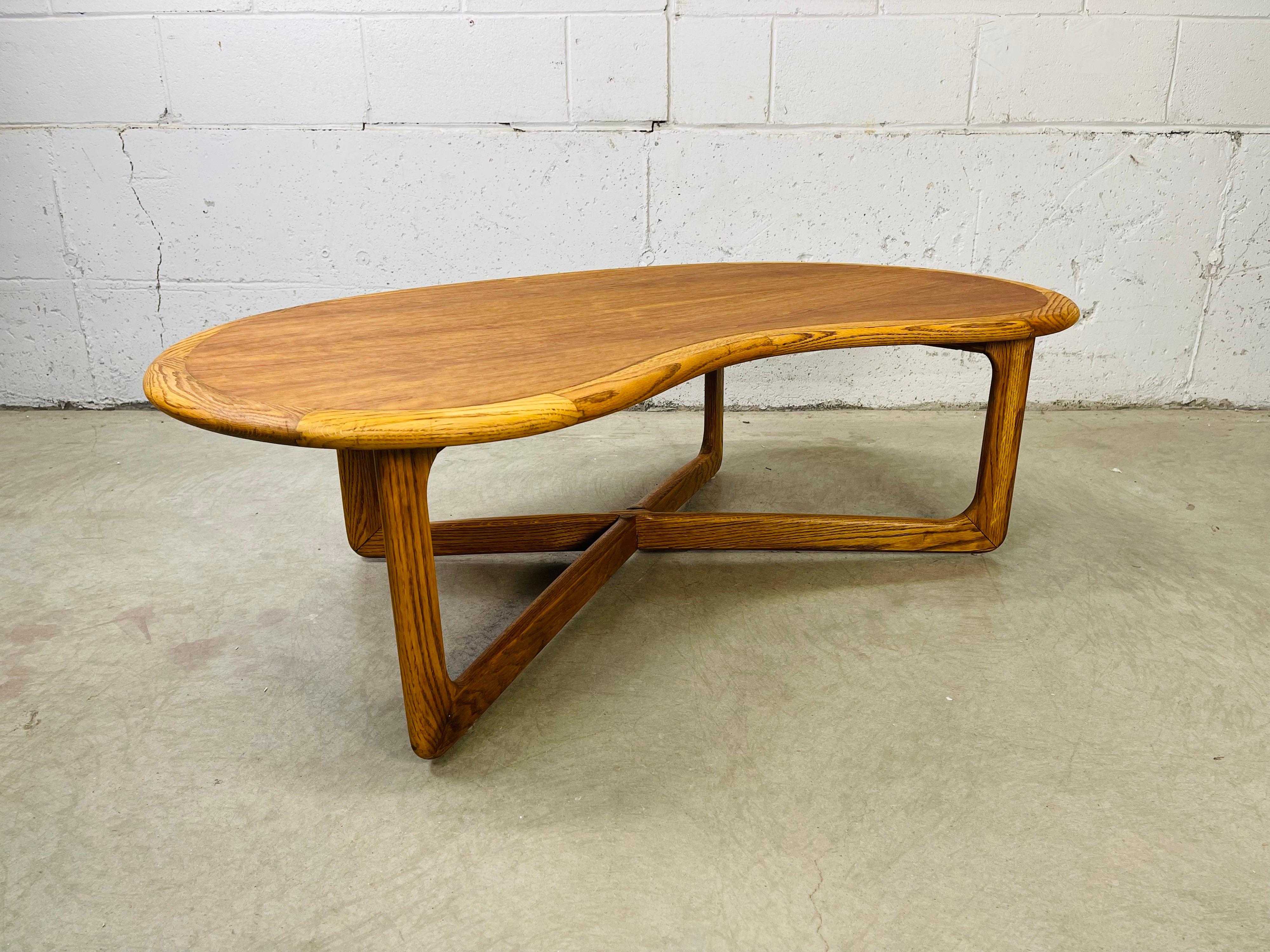 Vintage 1970s Lane Furniture Co walnut wood kidney shaped coffee table with oak edges and base. The X-base has stretcher style legs. Marked underneath.