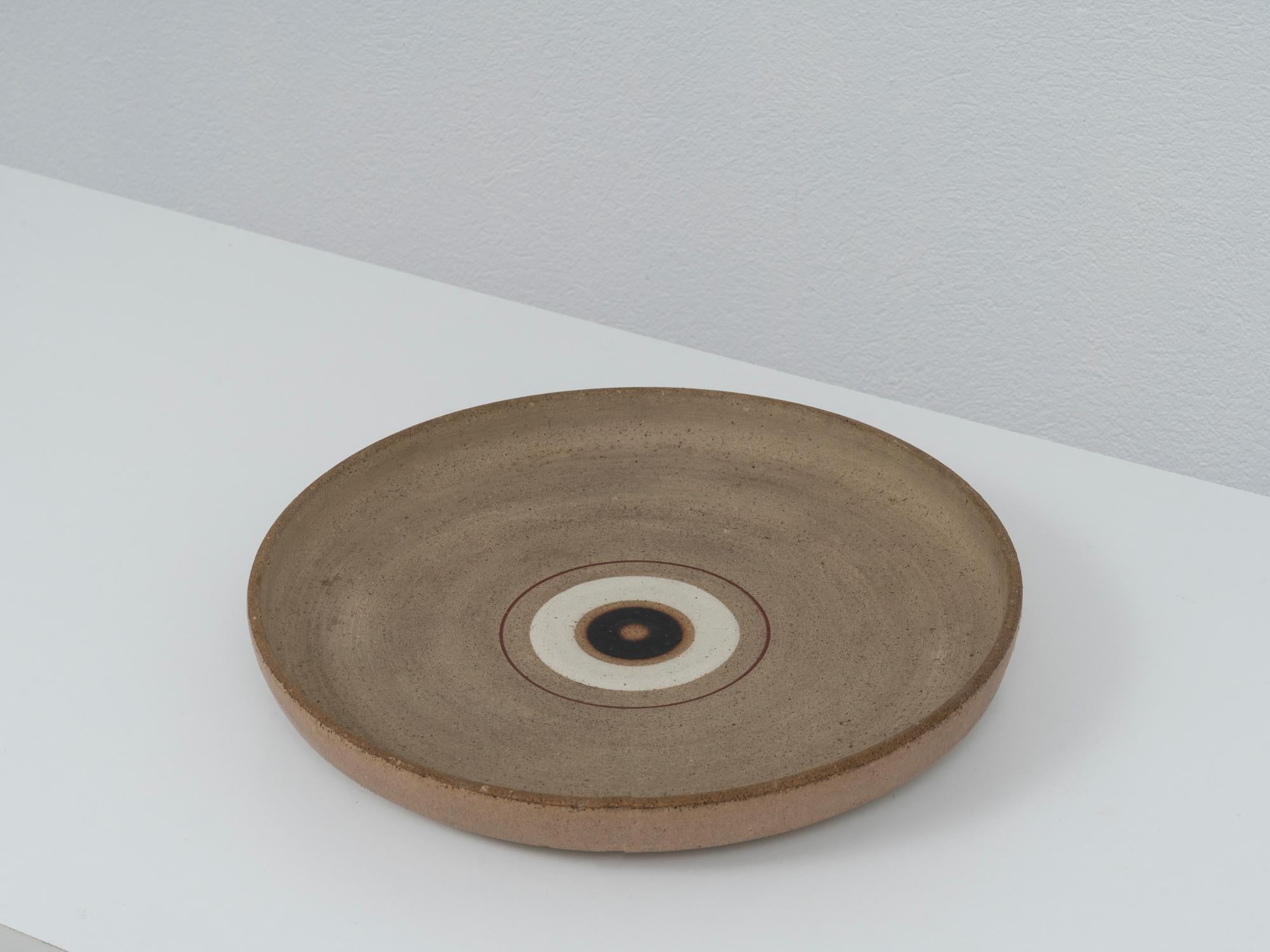 Beautiful 1970s large center plate by Italian ceramic master Bruno Gambone, in rich earthly tones with burnished brown, cream and crimson accents. Tactile raw finish with smooth details, decorated with Gambone's iconic concentric decor.
The piece