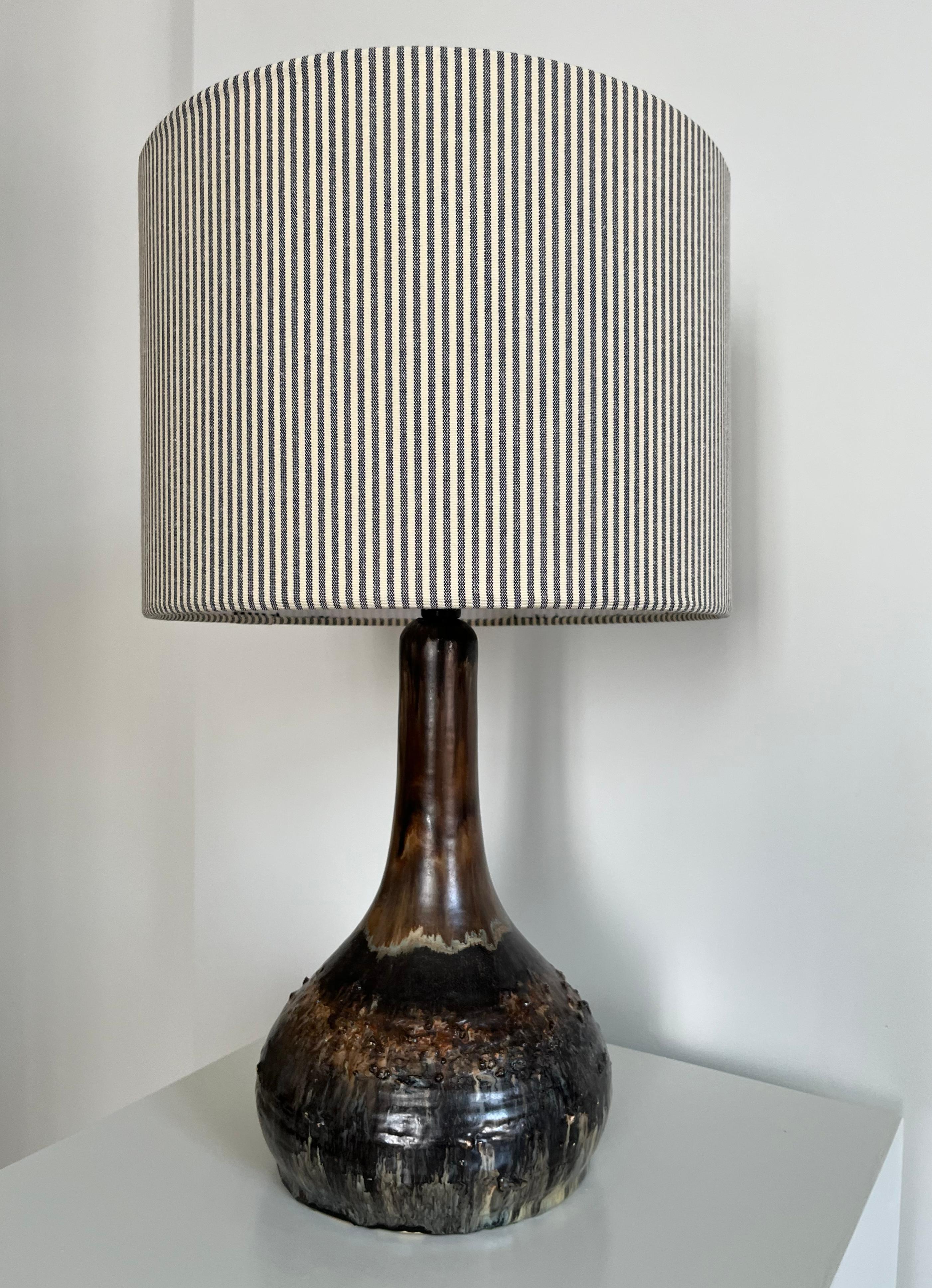 Large Danish table lamp in ceramics decorated with glossy lava glaze and detailed decorations in the ceramic. Glaze in nuances of brown, and a very light green. Handmade in Denmark in the 1970s. 
Sold without the shade.

Height: 36 cm (14.2 in) with
