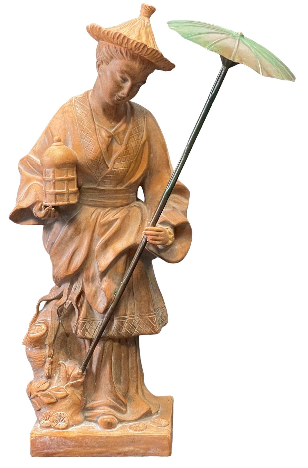 This is a 1970s large scale chinoiserie figurine depicting a female holding a brass umbrella. This piece is attributed to Chapman and in very good condition. 