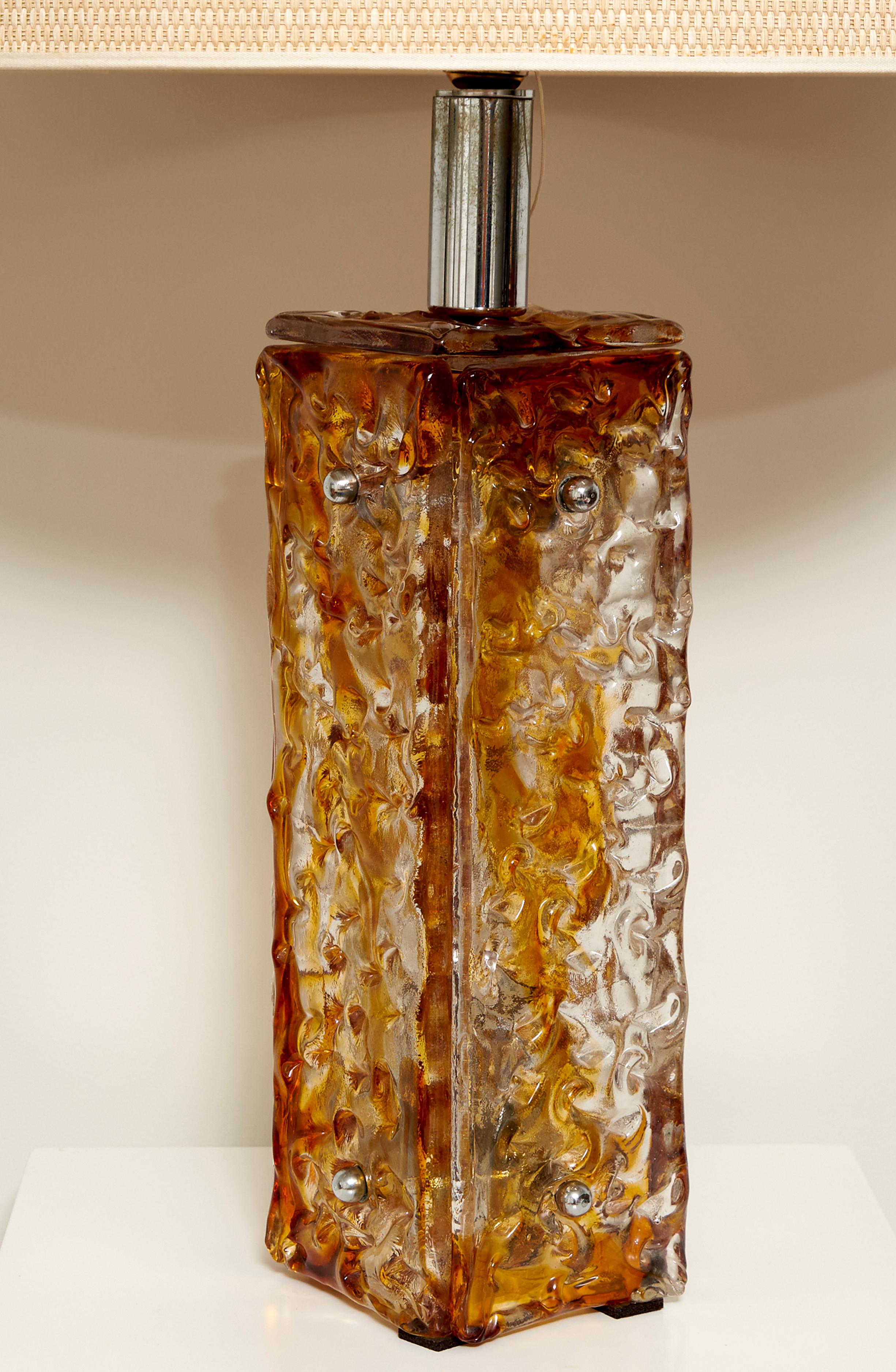Lampe de table grand format de designer anonyme en verre de Murano et acier chromé. Italie, 1970

La base est structurée en quatre dalles à la texture organique et à la teinte brun-orange vissée à une structure métallique. L'intérieur du socle peut