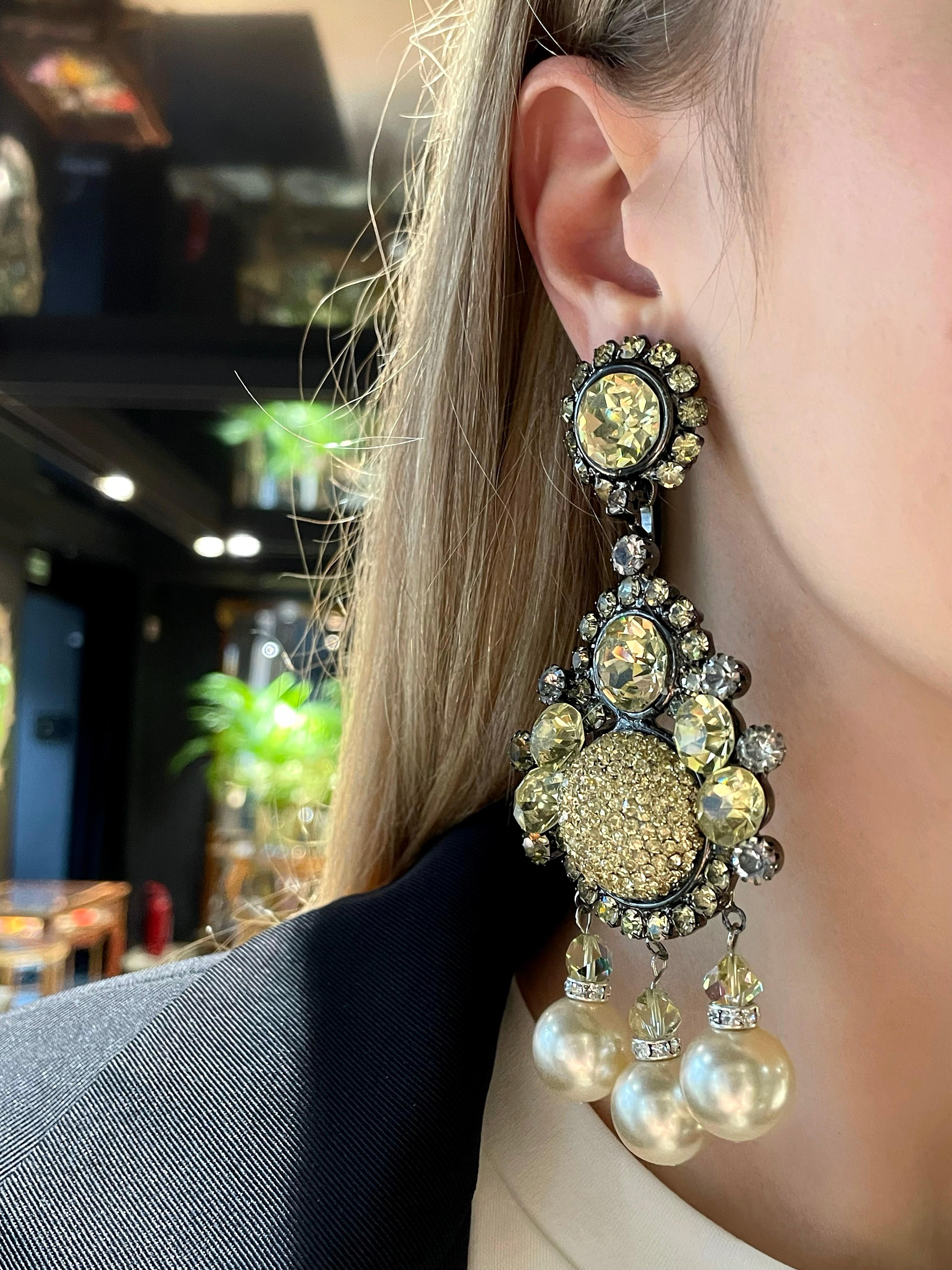 This is a pair of stunning massive clip on earrings designed by Lawrence VRBA in 1970s. The piece is crafted in base metal. It features shiny light green crystals and creamy faux pearls. 

Signed: “Lawrence VRBA”

Length: 12cm
Width (at max):