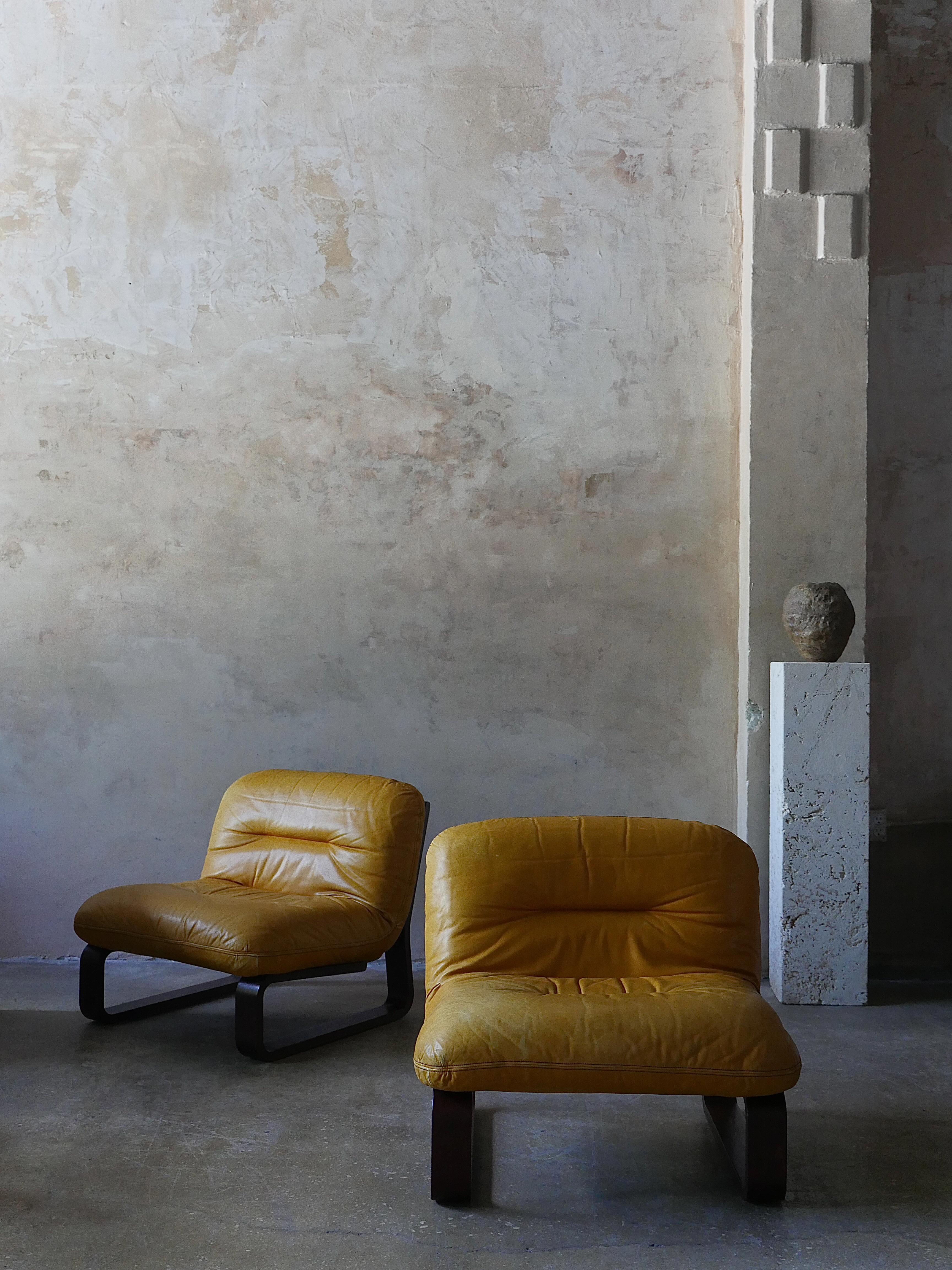 Pair of 1970s rosewood and patinated leather lounge chairs, on bentwood cantilever frames. Sink into total comfort with the supple leather and plush cushions of these timeless chairs.