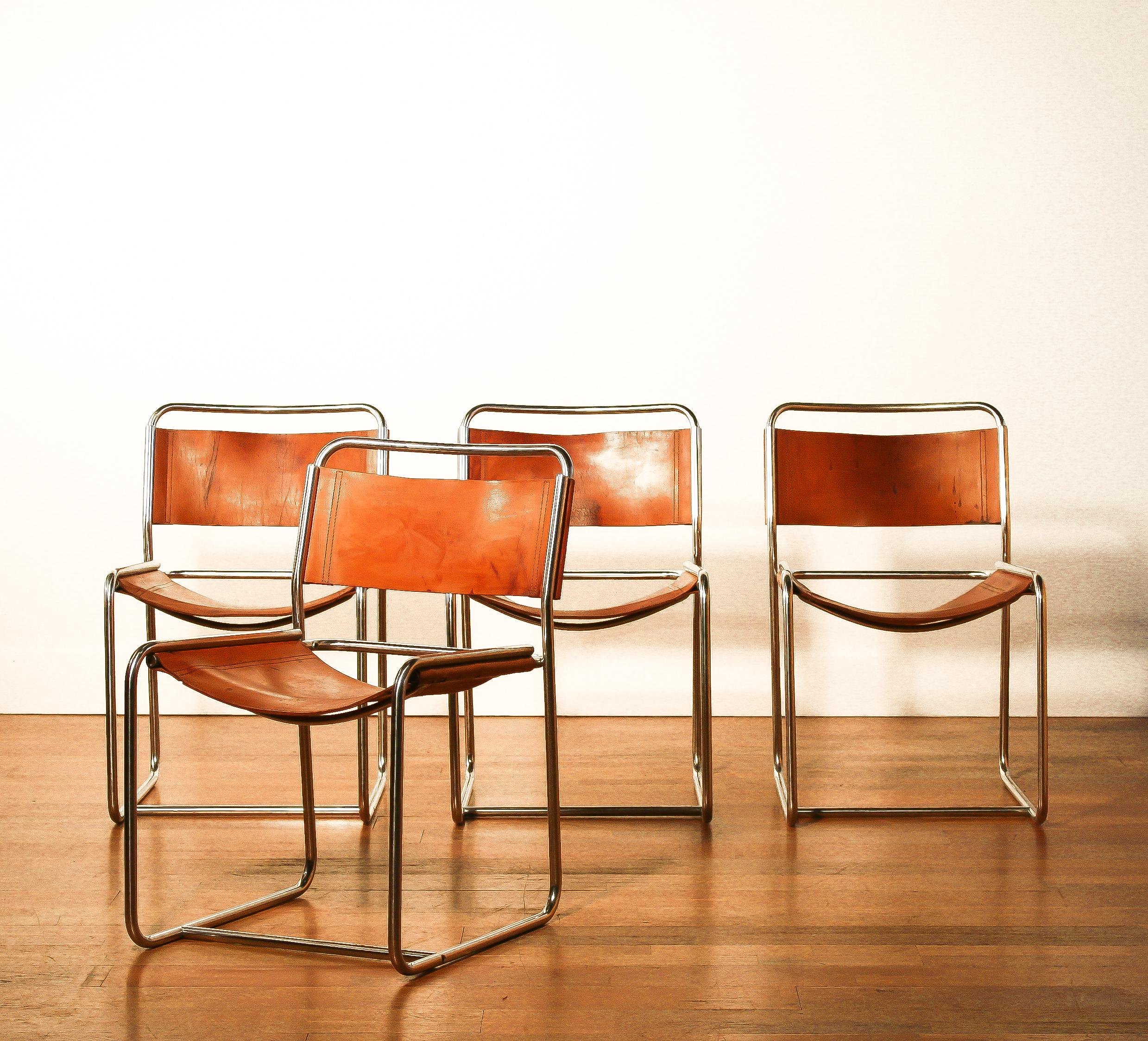 A nice set of four dining chairs designed by Paul Ibens & Clair Bataille.
The seat and the backrest are made of sturdy cognac leather. 
The frame consists of steel tube that is shaped like a cube. 
The chairs are in a very nice used