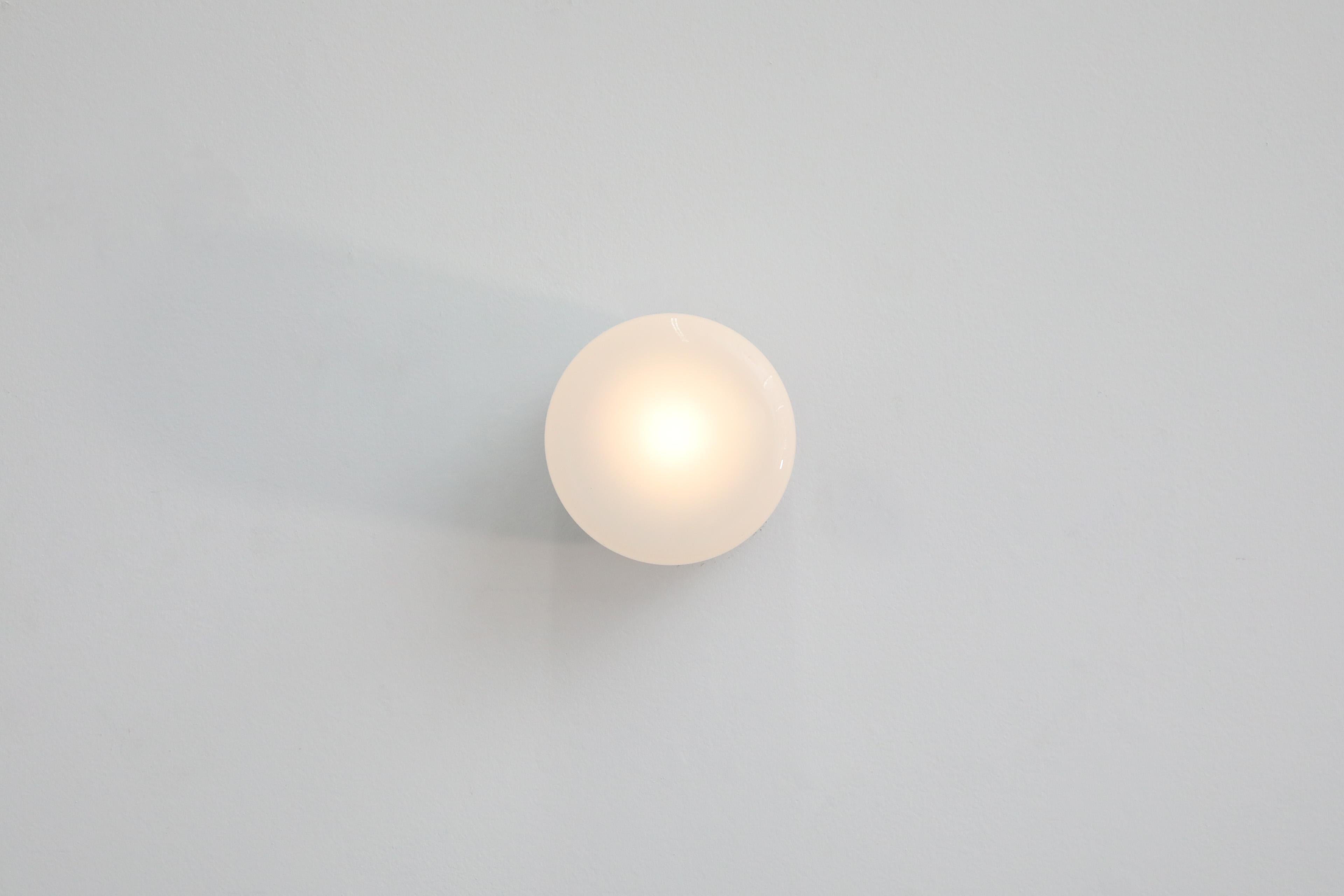 1970's large rounded milk glass flush mounted light on black Bakelite base. Can be used as a ceiling or wall mount sconce. In original condition with age appropriate wear.