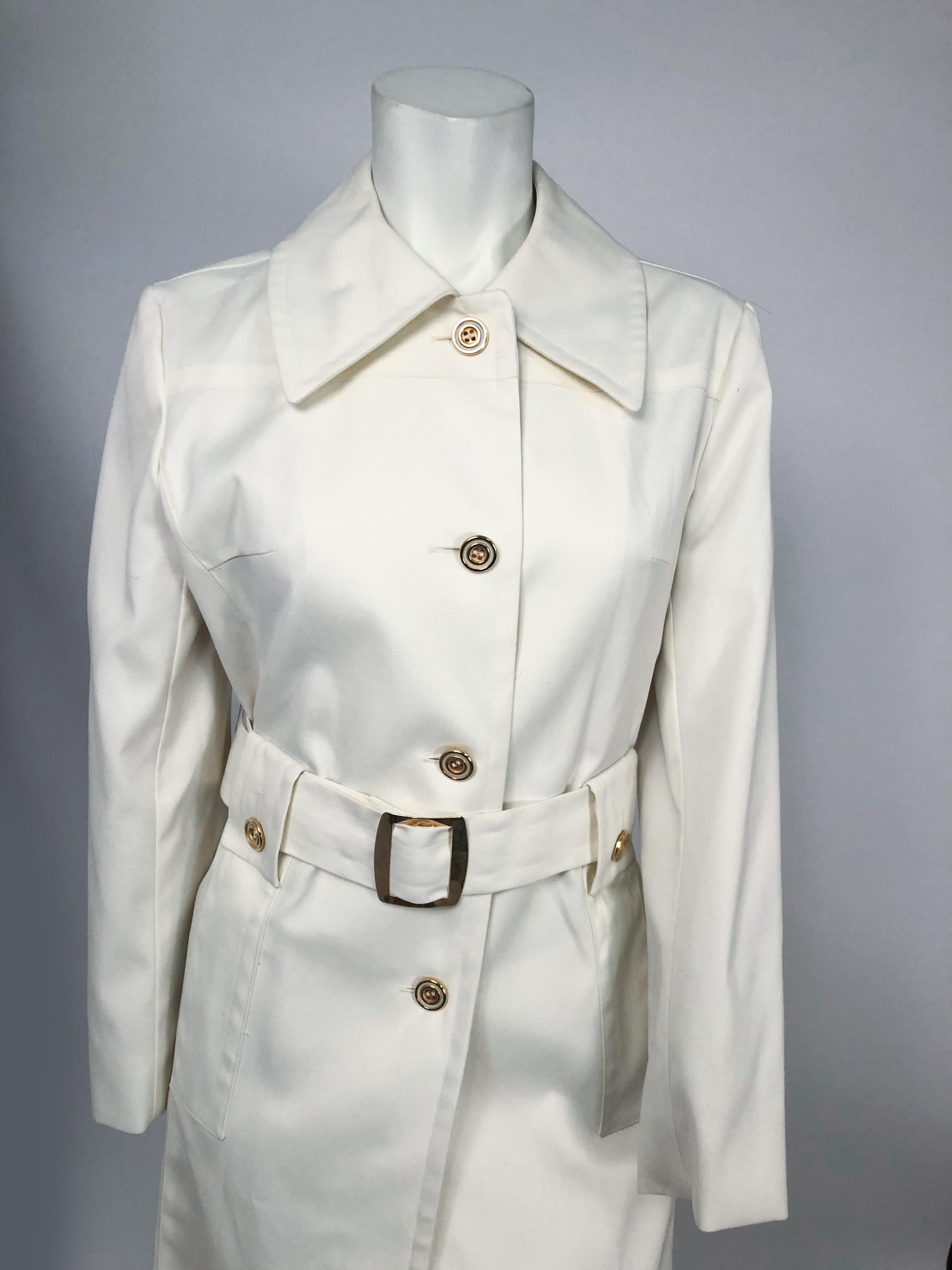 1970s London Fog Cream Trench with brass buttons/buckle, wide collar, and pockets.