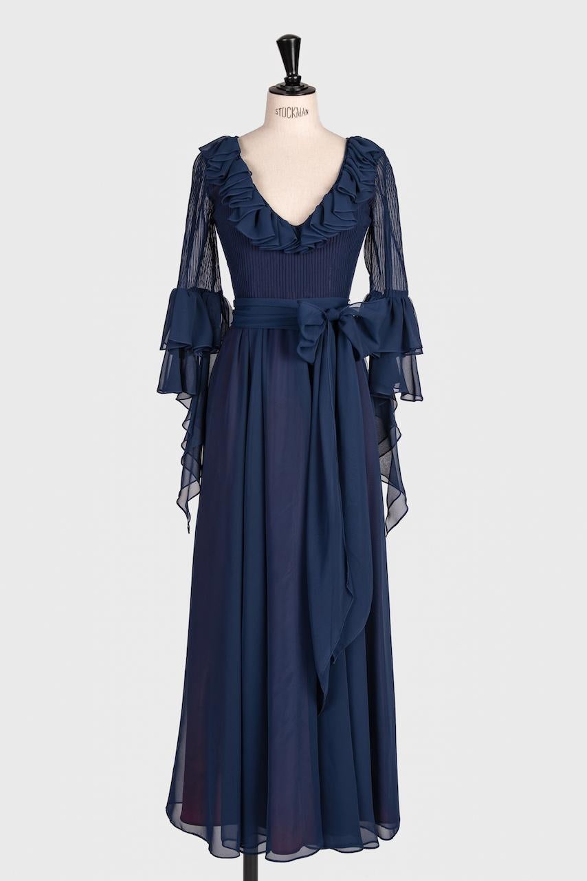 Il s'agit d'une belle robe de soirée en mousseline bleue à l'encre attribuée à Louis Fraud Paris des années 1970. À cette époque, la Maison Fraud était bien établie et, en 1978, le couturier a remporté le prestigieux « Golden Thimble Award ». Cette