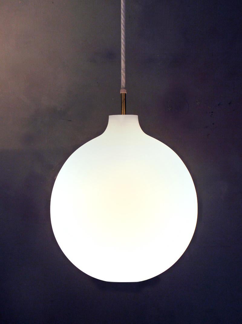 Elegante Satellite Pendelleuchte mit einem mundgeblasenen weißen Opalglasschirm auf einem Messingstiel mit einer Stoffkordel, entworfen von Vilhelm Wohlert im Jahr 1959. Allgemeine indirekte Beleuchtung. Direkte Beleuchtung durch die Öffnung an der