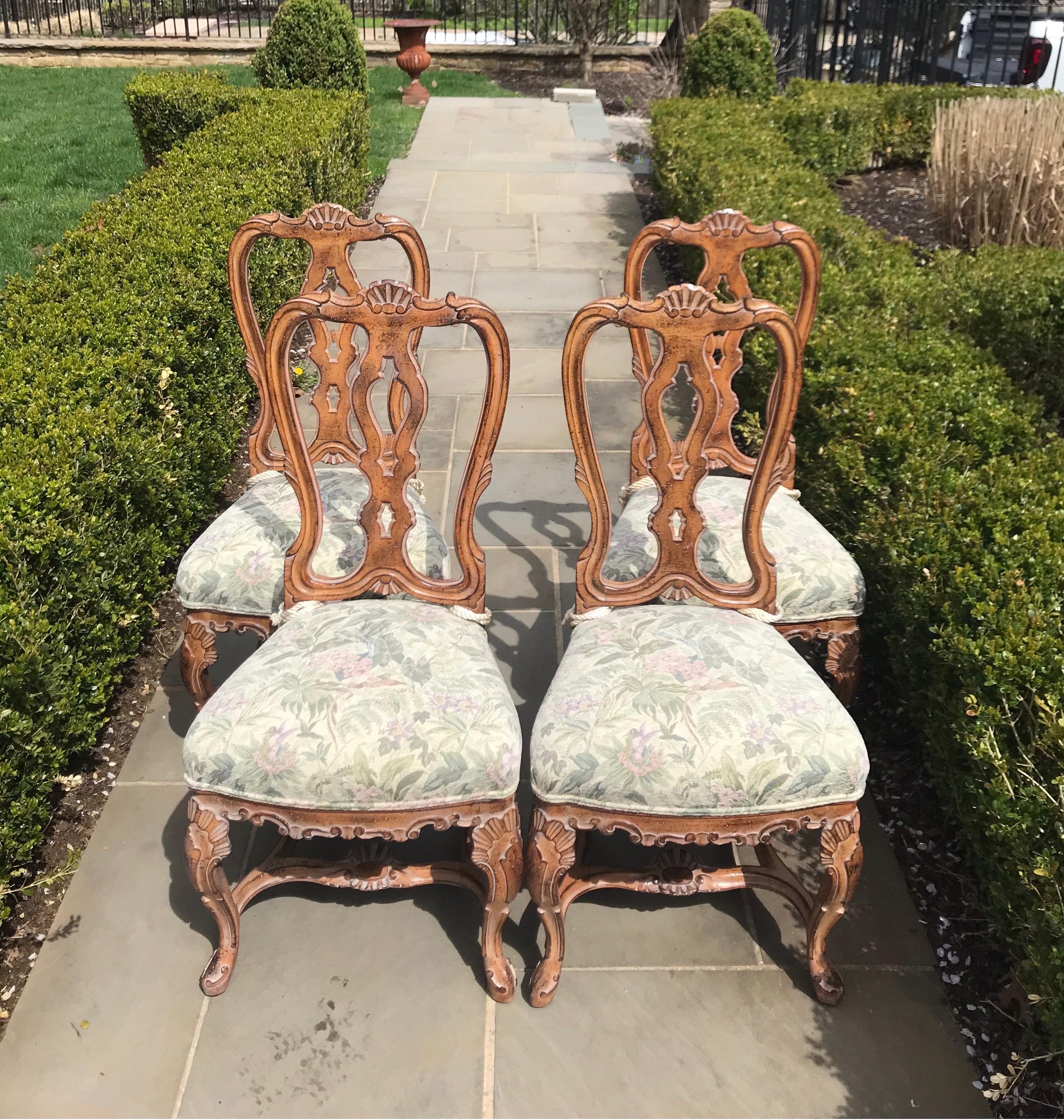 A remarkable vintage set of 4 Italian dining chairs handcrafted wood featuring four chairs with grotto-style carved details throughout the entire frame. The seat is upholstered in a beautiful tapestry and rests on sturdy carved stretched legs. They