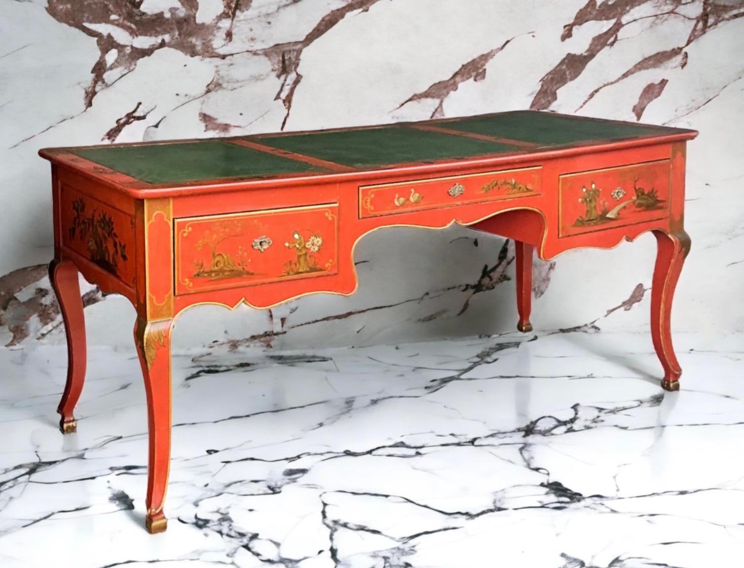 This is a beautiful vibrant Louis XV style chinoiserie desk by Baker Furniture Company. It is a Hermes orange with a bright green leather top. It has painted gilt accents and Chinese pastoral scenes throughout both sides of the desk. It is marked,