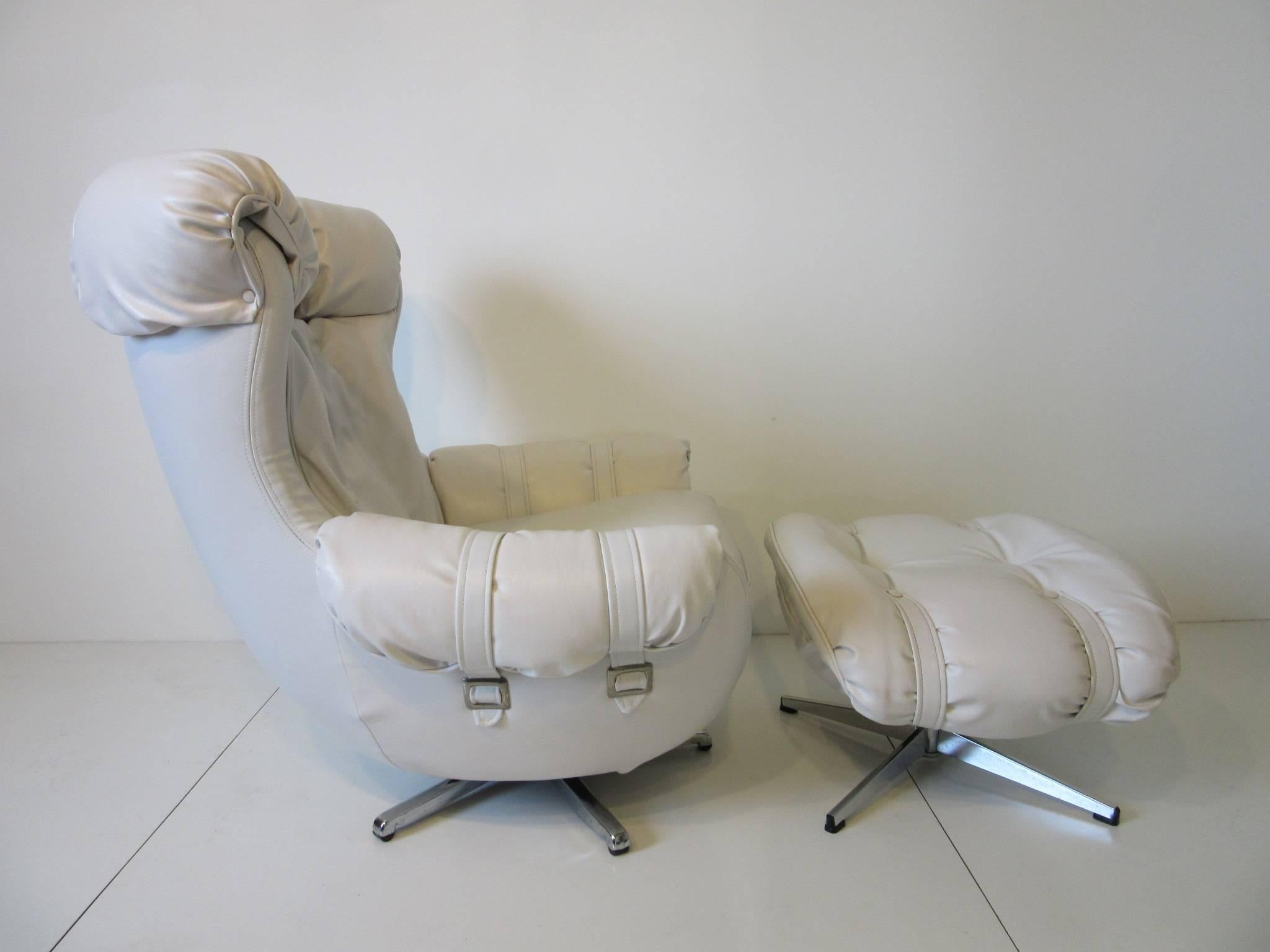A pair of white Naugahyde swiveling and rocking lounge chairs with silver buckles and star bases and white straps set the style of the 1970s and Studio 54. Measurement for the ottoman is 28