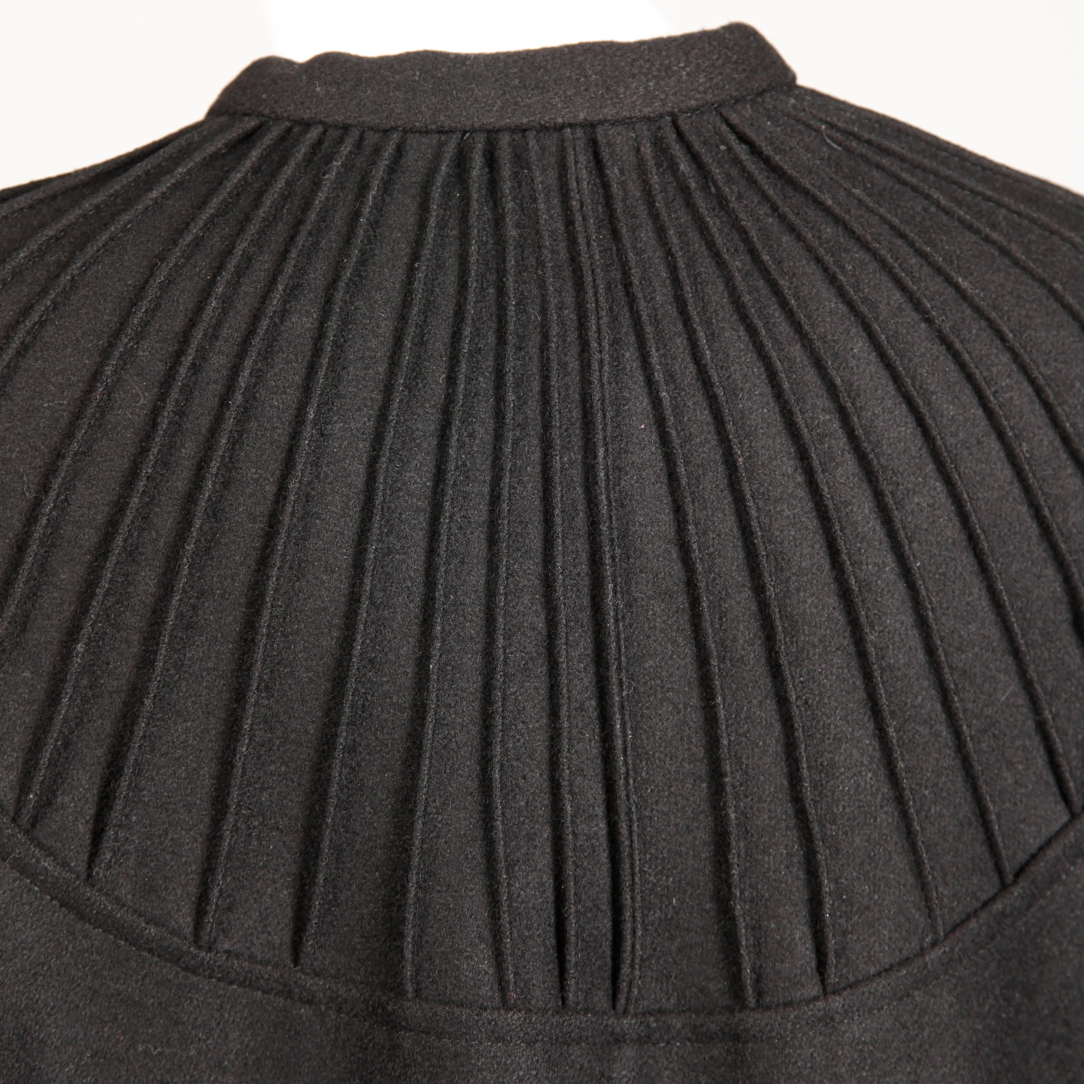 Heavy and warm vintage 1970s black wool cape coat by Luba Rudenko. This cape has top stitching around the neckline in a radial design and an ascot tie at the neck. It hooks in front with a single hook closure. Unlined. Will fit most sizes on account