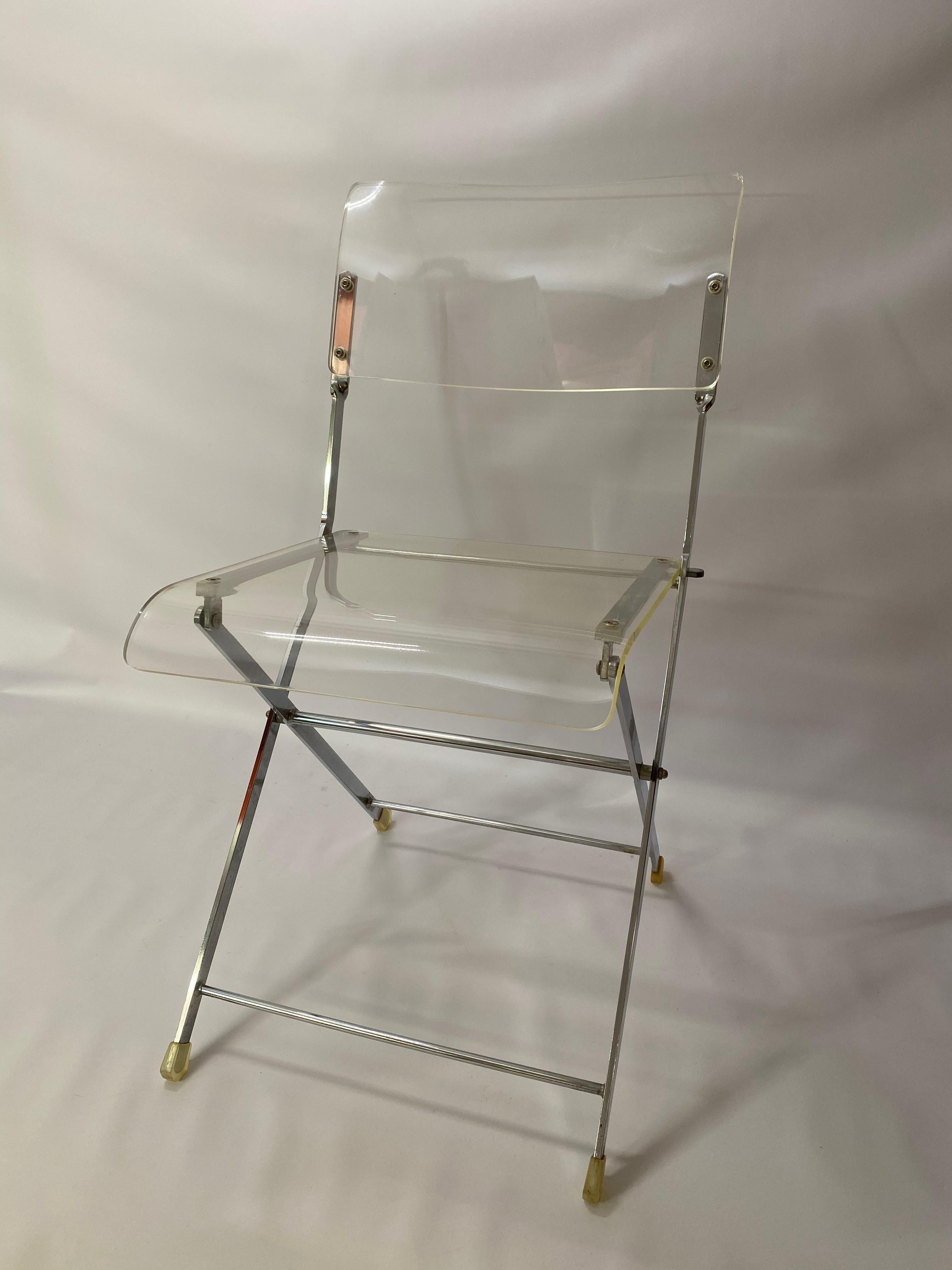 Folding Lucite and chrome chair. The Lucite is amazingly clear. Folds up flat for mobility and convenience. Comfortable enough as a desk, dining, accent chair chair. Circa 1970. Good condition with a few minor scratches and a small nick to the edge.