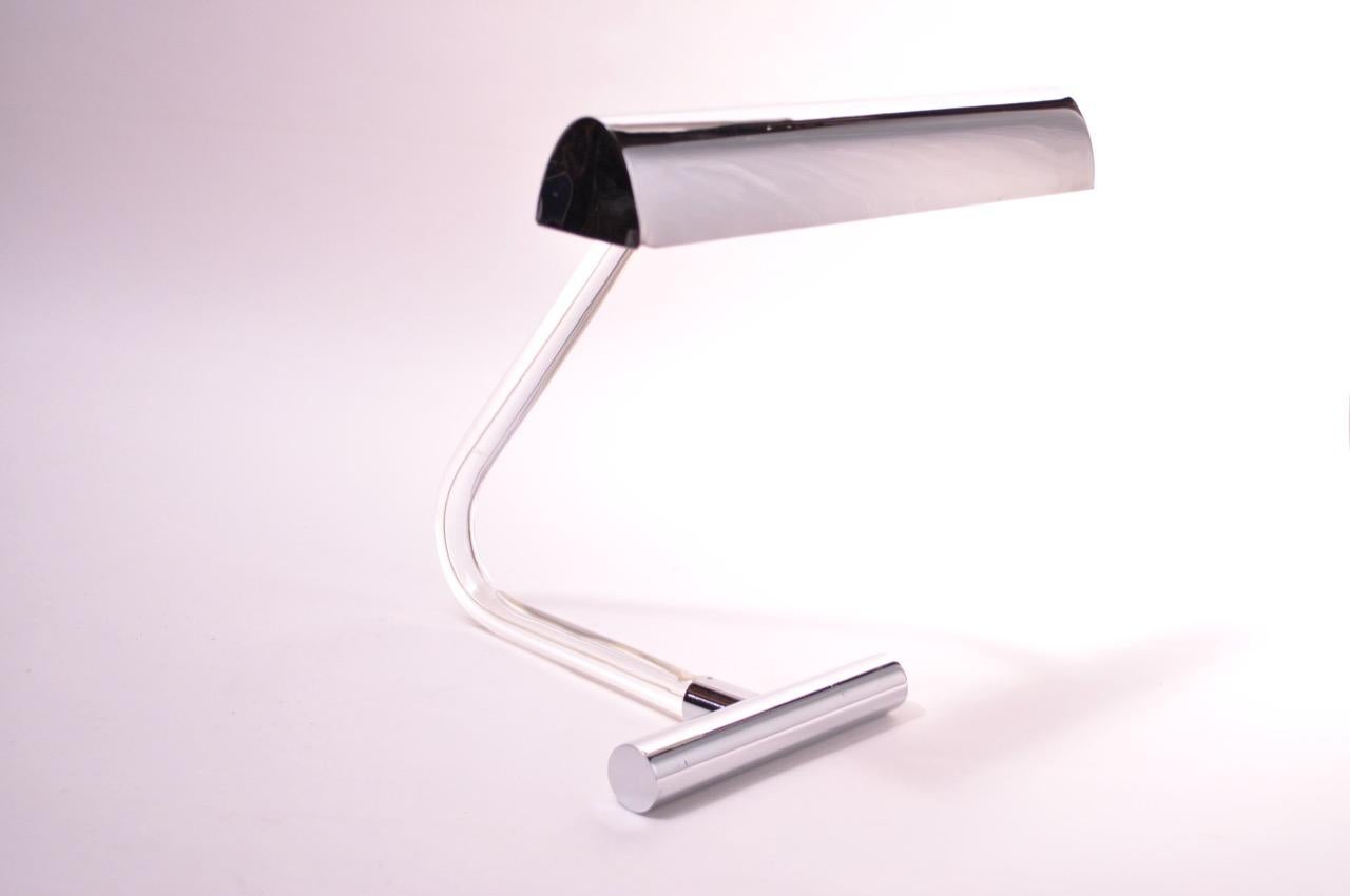 Striking table lamp designed in the 1970s by Peter Hamburger for George Kovacs as part of his “Crylicord” collection. Features a curved tubular Lucite stem with chrome shade and hardware with a chromed-steel counterweight base. Retains the original