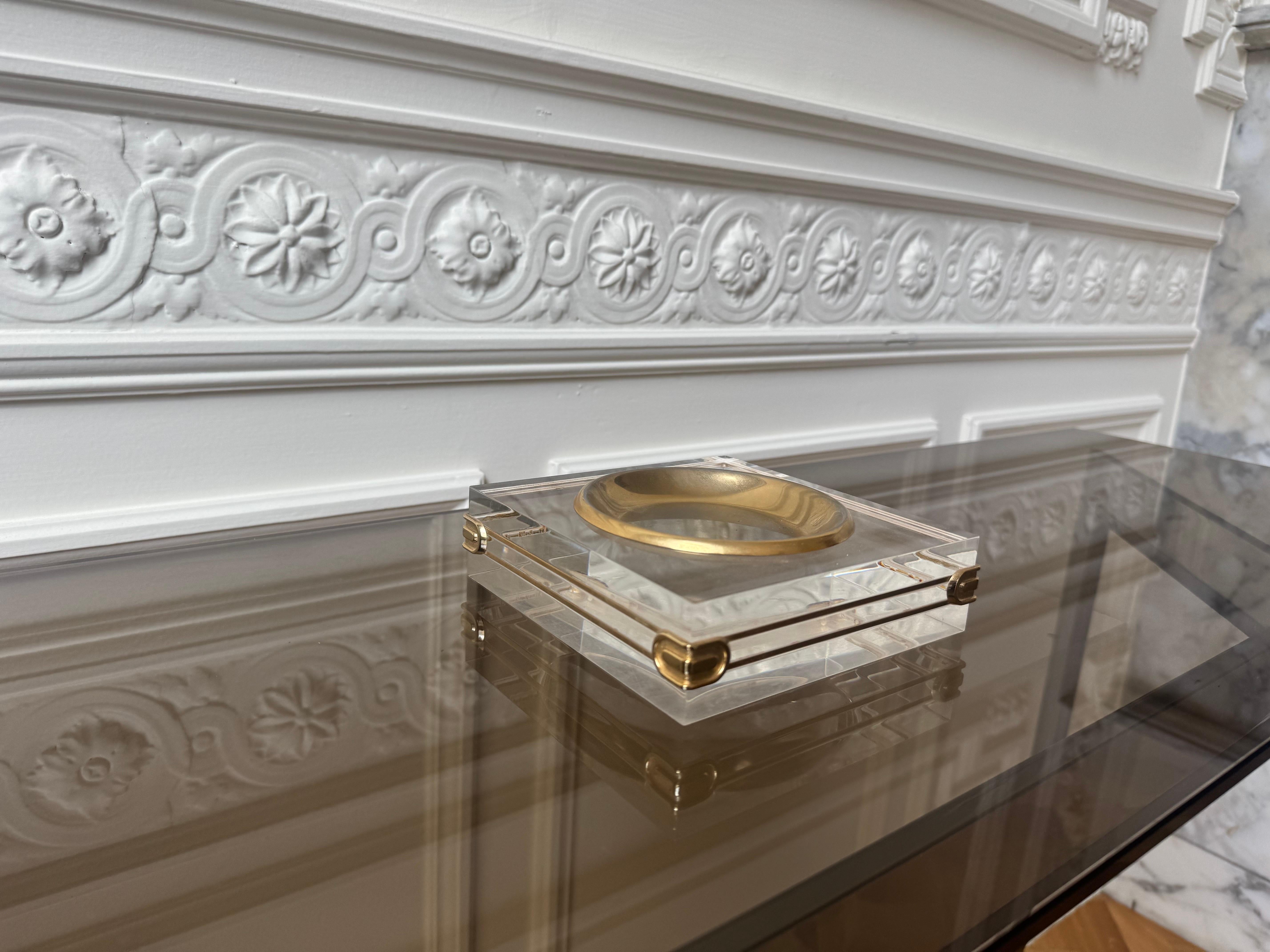 Questa raffinata videopoche italiana degli anni '70 è realizzata in lucite spessa e impilata con dettagli in metallo dorato, per una presenza elegante e scultorea. Il piatto centrale concavo, anch'esso in metallo dorato, lo rende ideale come