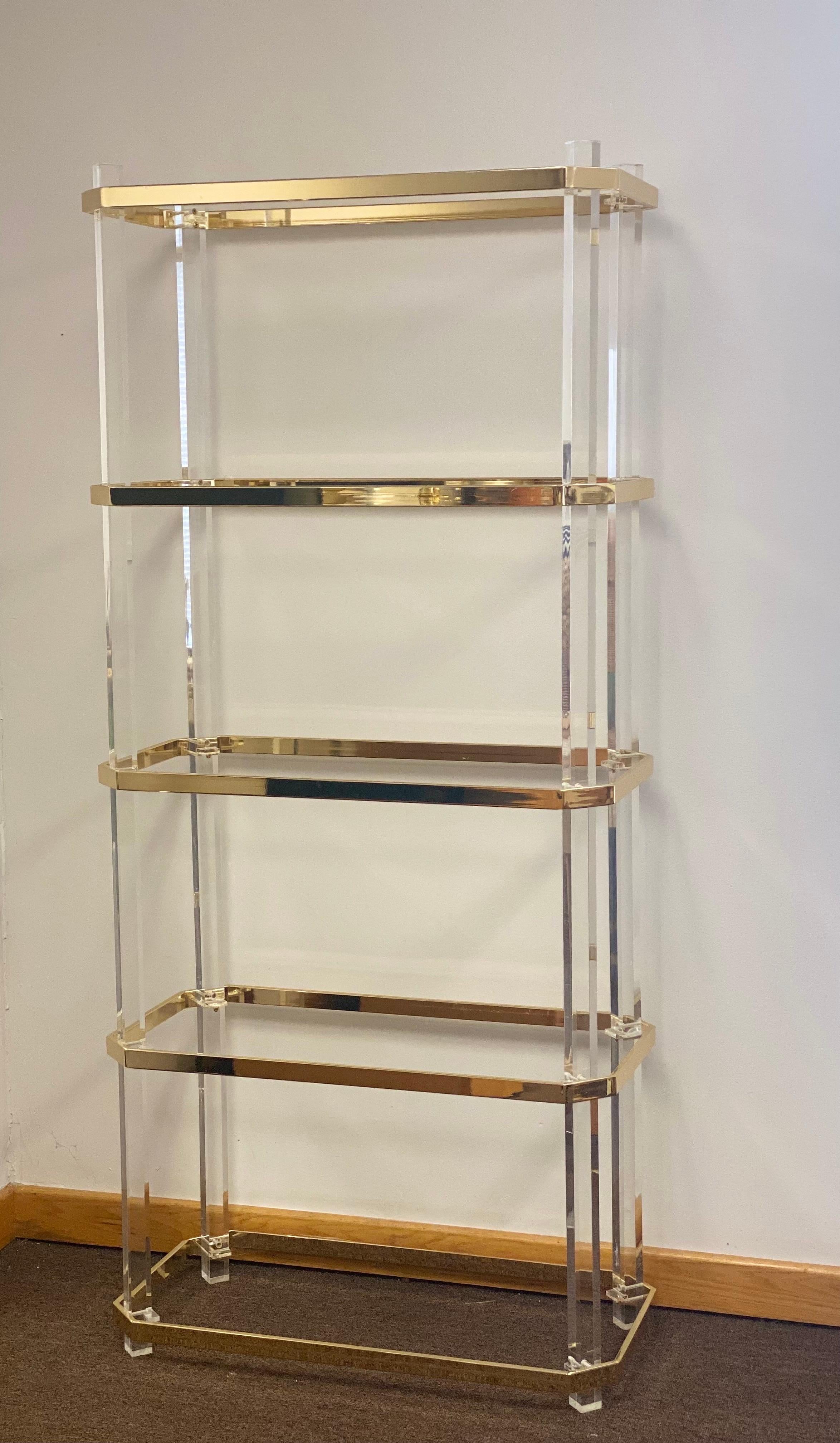 We are very pleased to offer a stunning etagere, circa the 1970s. Beautiful clear Lucite, polished brass and clear glass come together to form a streamlined piece for storage and display. Perfect for any décor due to its blend of simplicity and