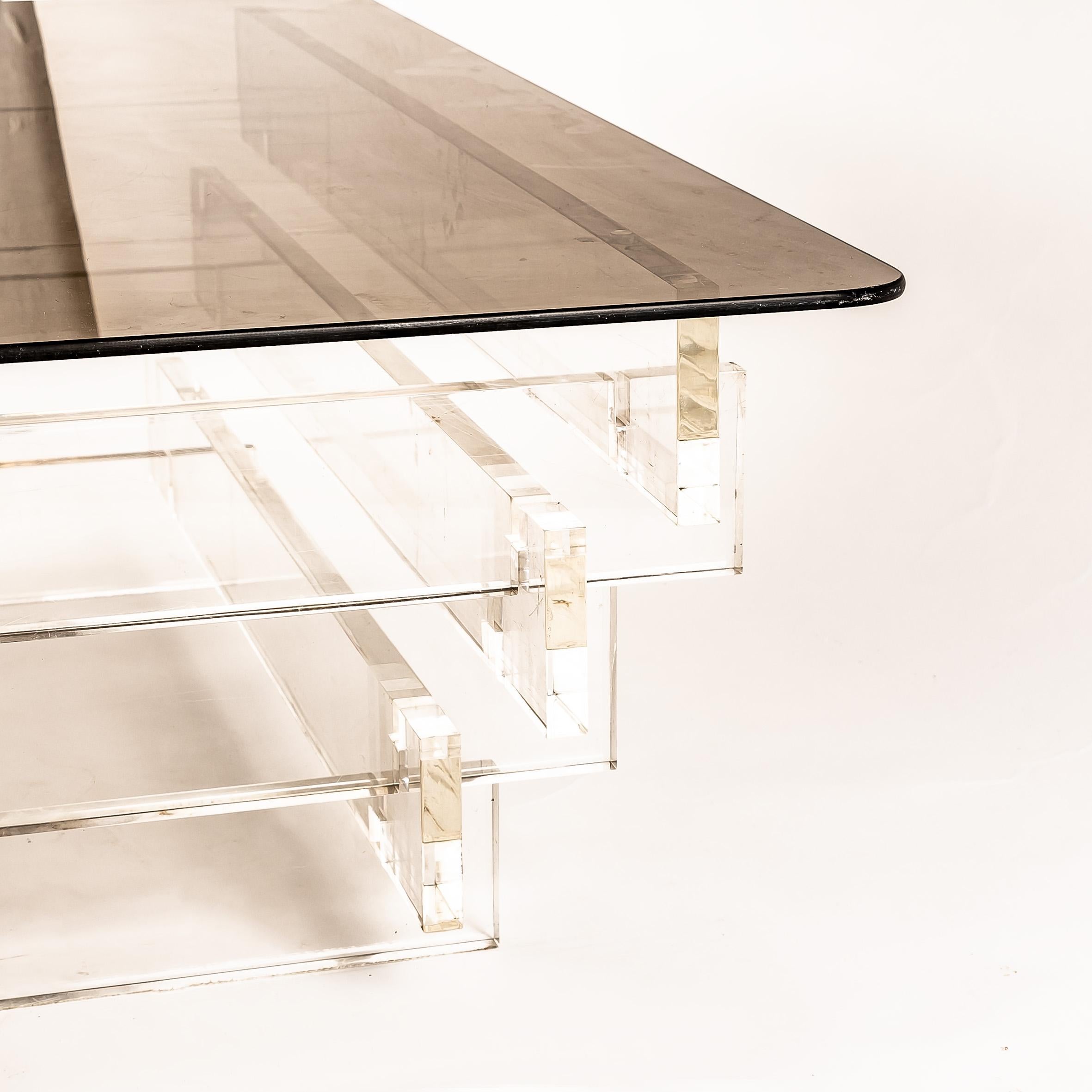 Elevate your interior with this stunning 1970s Lucite and smoked glass coffee table, a perfect blend of transparency, elegance, and bold mid-century modern style. The clear Lucite base provides a light, floating appearance, while the smoked glass