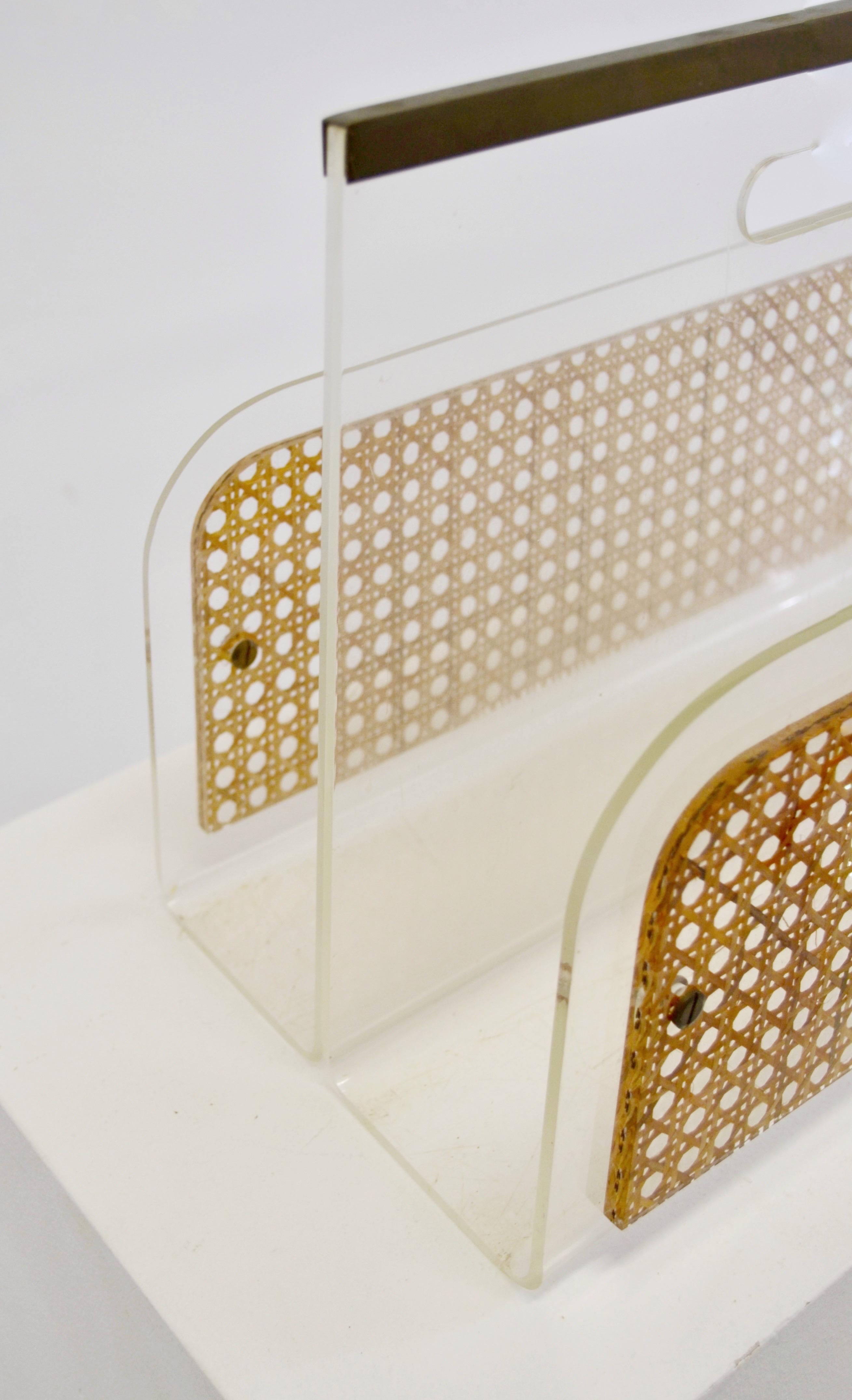 Rare porte-revues sophistiqué créé pour la collection Home de Christian Dior dans les années 1970.
Le design associe des panneaux en Lucite claire, du cannage naturel tressé et des accents en laiton, avec une poignée intégrée sculpturale qui met en