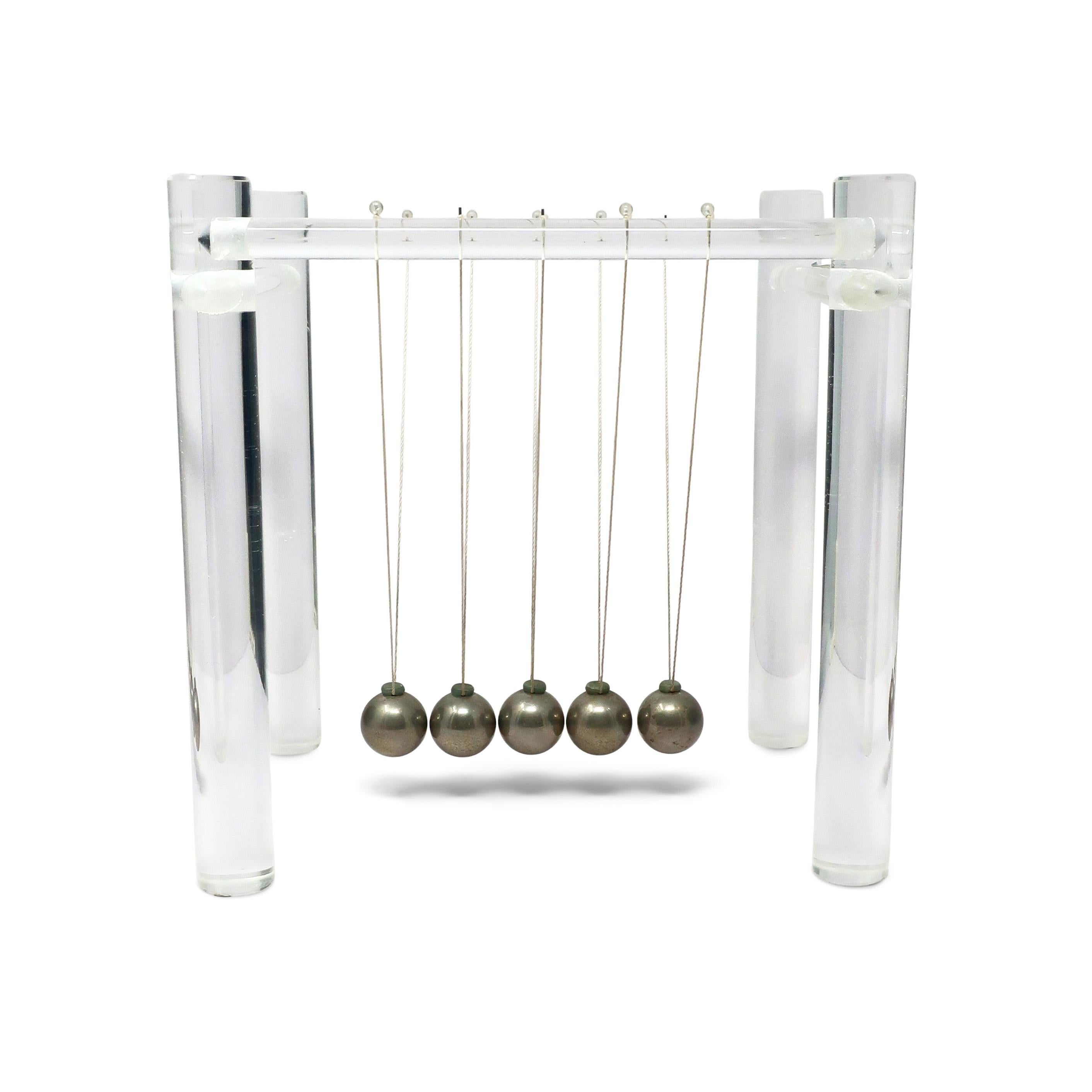 A fantastic Mid-Century Modern lucite Newton's cradle. Pull one of the metal balls back and let it swing and you create motion that just keeps going with a satisfying click, click, click! Lucite frame, metal balls, and thread hold this simple