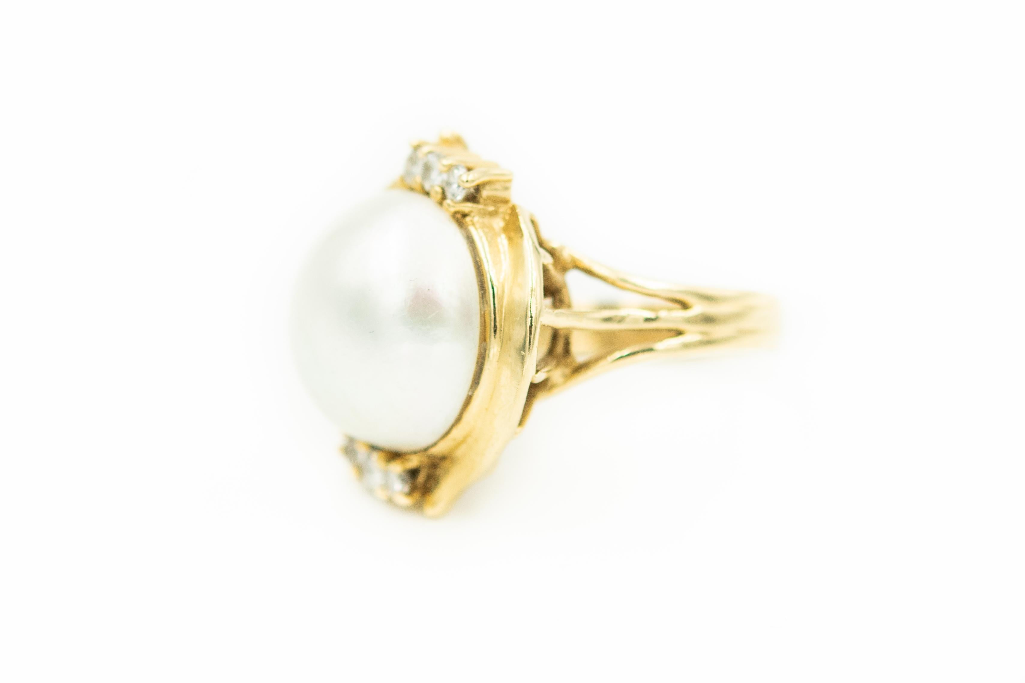 Mabe Pearl dome ring accented by 3 prong set diamonds on either side in a gold styled rim.  The approximate total diamond weight is .12 carats.  The ring is 14k yellow gold. The mabe pearl is over 14mm wide.

It is a US size 7.25

