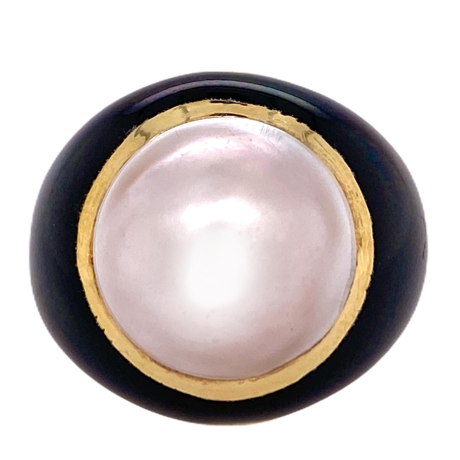 Beautiful mabe pearl and black onyx cocktail ring fashioned in 18 karat yellow gold. The ring features a white mabe pearl bezel set in an yellow gold bezel and surrounding black onyx. The ring is in excellent condition, measures 20mm in width, 10mm