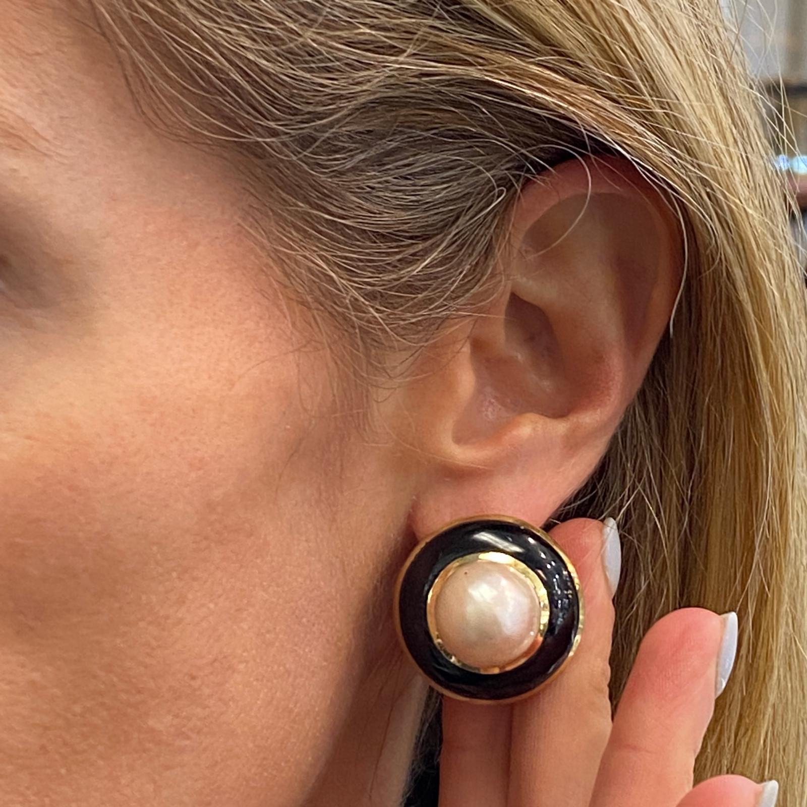 Vintage mabe pearl and black onyx earrings crafted in 18 karat yellow gold. The mabe pearls are bezel set in yellow gold and surrounded by black onyx gemstone. The earrings measure 1.0 inch in length, 1.0 inch in width, and feature lever backs. 