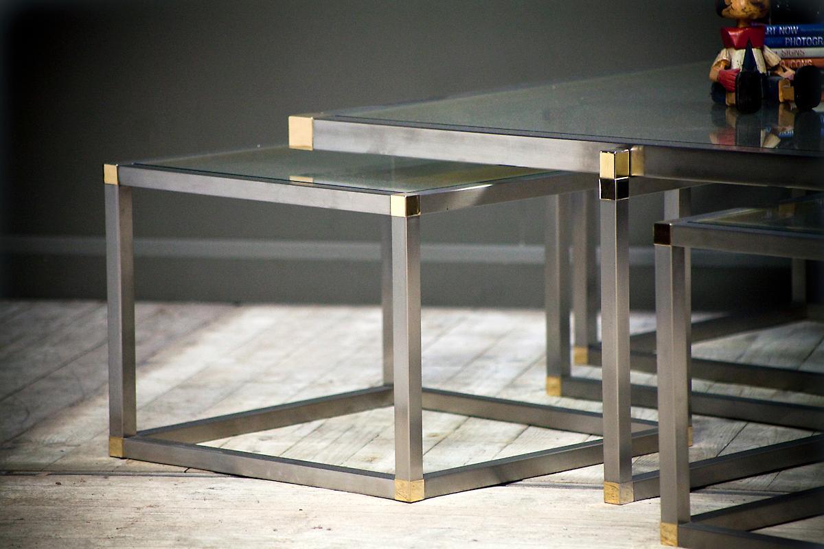 Beautiful 1970's Maison Charles coffee table of glass, brass and chrome with 4 nested tables. Dimensions of small tables: height 37 cm, width 52 cm, depth 52 cm. 5 tables in total. Accessories not included. 