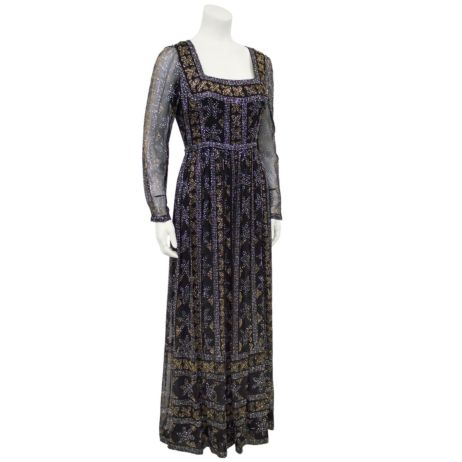 Elegante vestido de Elinor Simmons para Malcom Starr de los años 70, de gasa negra y cintura imperio, con detalles de destellos lineales plateados y dorados. El tipo de vestido que cualquier mujer puede encontrar una ocasión para ponerse. Escote
