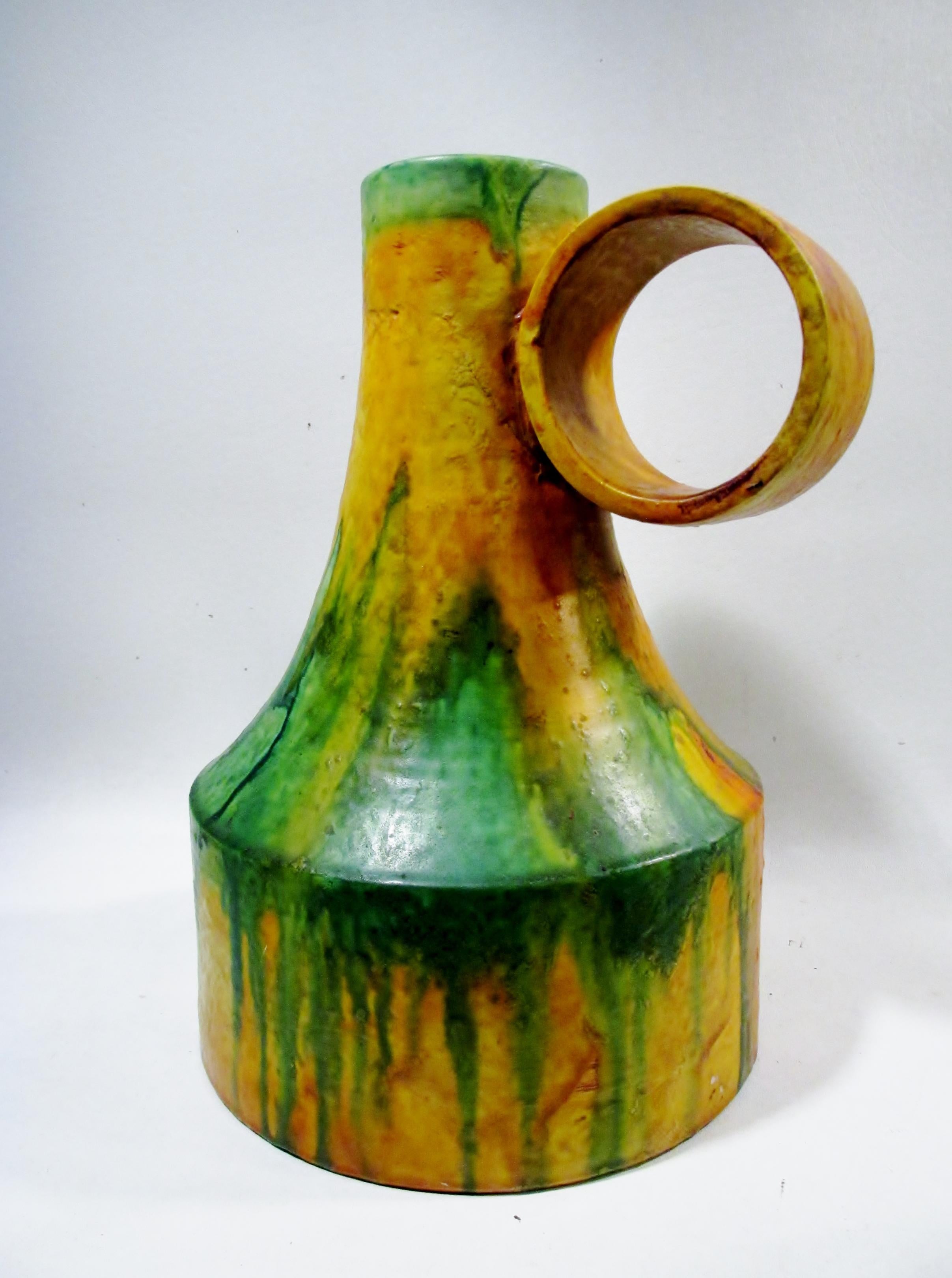 Outstanding large scale, 13.25” tall, 10” at widest, and 9” dia midcentury Italian art pottery loop handle vase from the studio of Marcello Fantoni. With his classic flambe drip glaze decoration in oranges, yellows, and greens. Retains the original