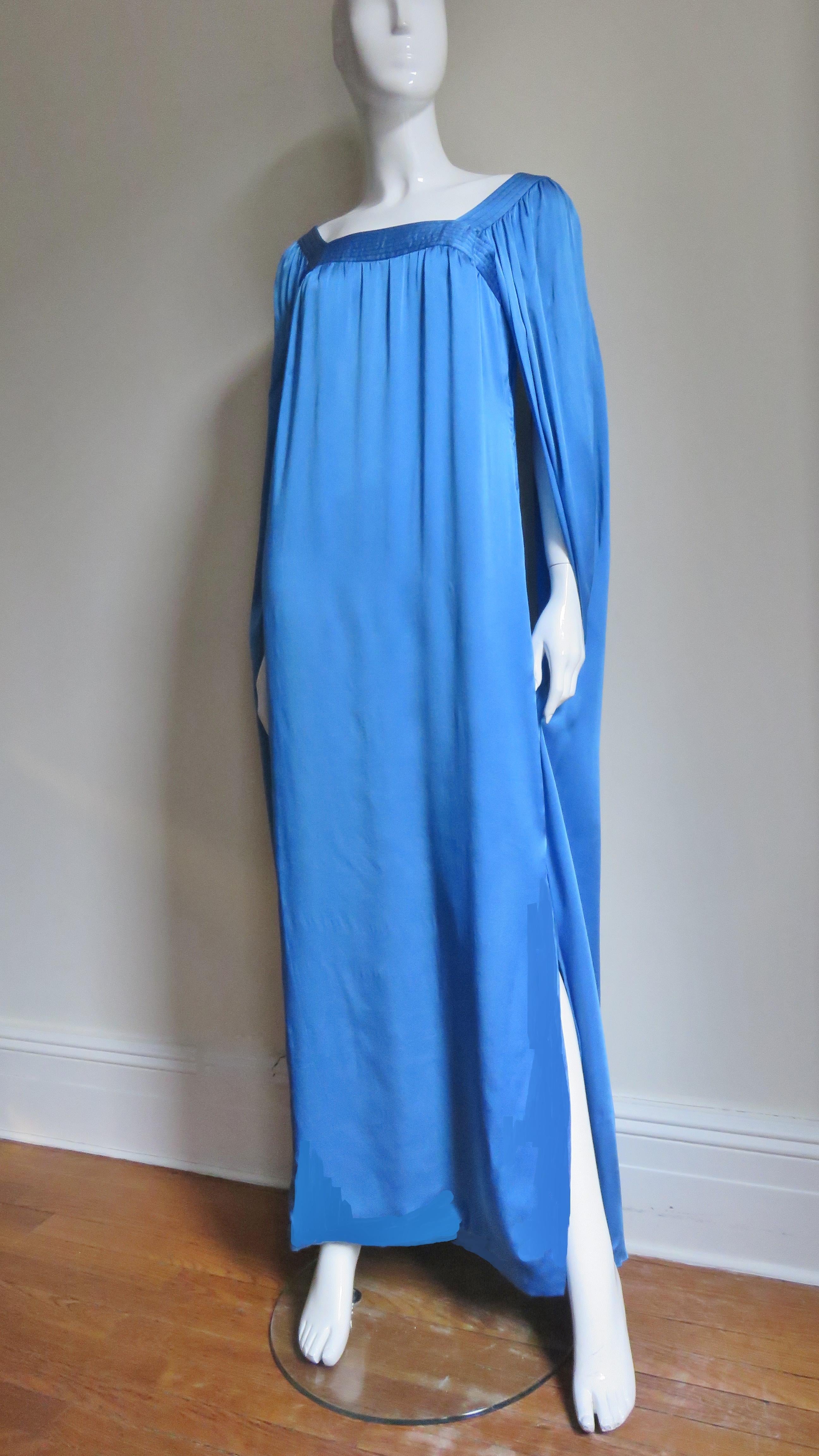 A beautiful blue silk charmeuse numbered couture gown from Christian Dior. The body of the floor length dress is gathered onto the square top stitched enhanced neckline front and back and the angel sleeves are also floor length and open underneath.