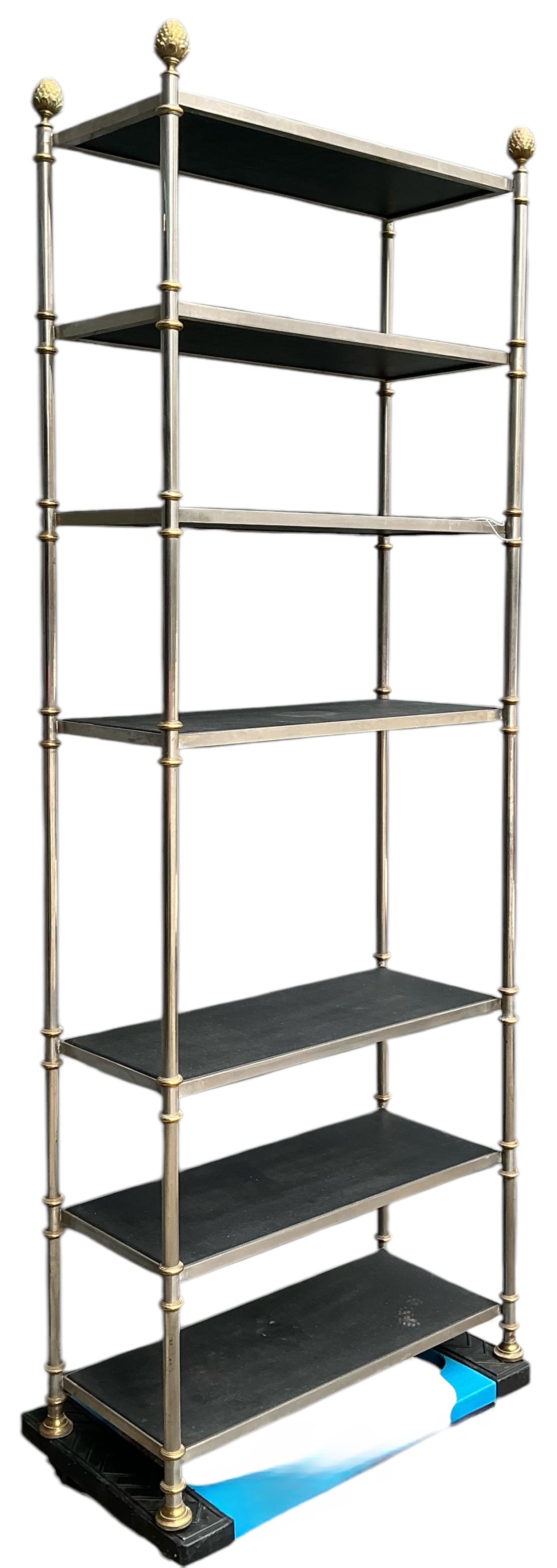 This is a 1970s Neo-classical style steel and brass etageres in the manner of Mason Jansen. The shelves are wrapped in black leather. There are four brass finials. The piece is most likely Italian and is in very good condition. 

Shipping is running