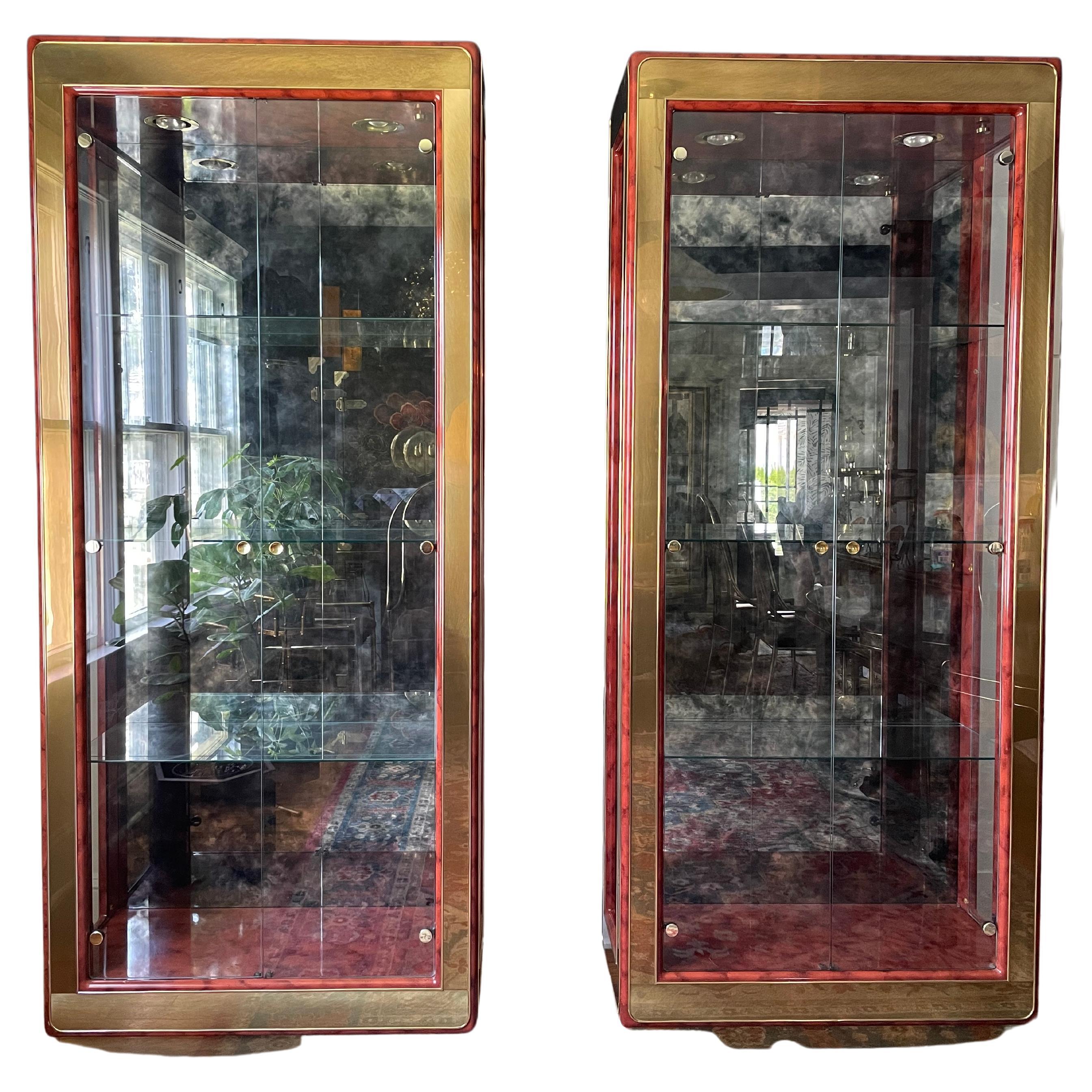 Pair of modern Mastercraft brass and glass display cabinets or vitrines with the highly sought after faux tortoise frame. These beautiful cabinets feature a brass over tortoise lacquered frame, three adjustable shelves with plate grooves, lights and