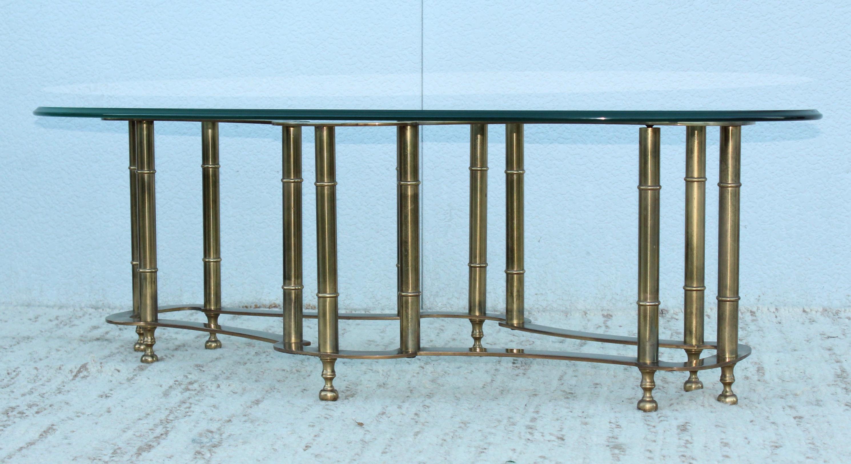 1970's Mid-Century Modern racetrack solid brass coffee table with glass top by Mastercraft, in vintage original condition with some wear and patina due to age and use there is some patina to the brass and some scratches to the glass, the base is