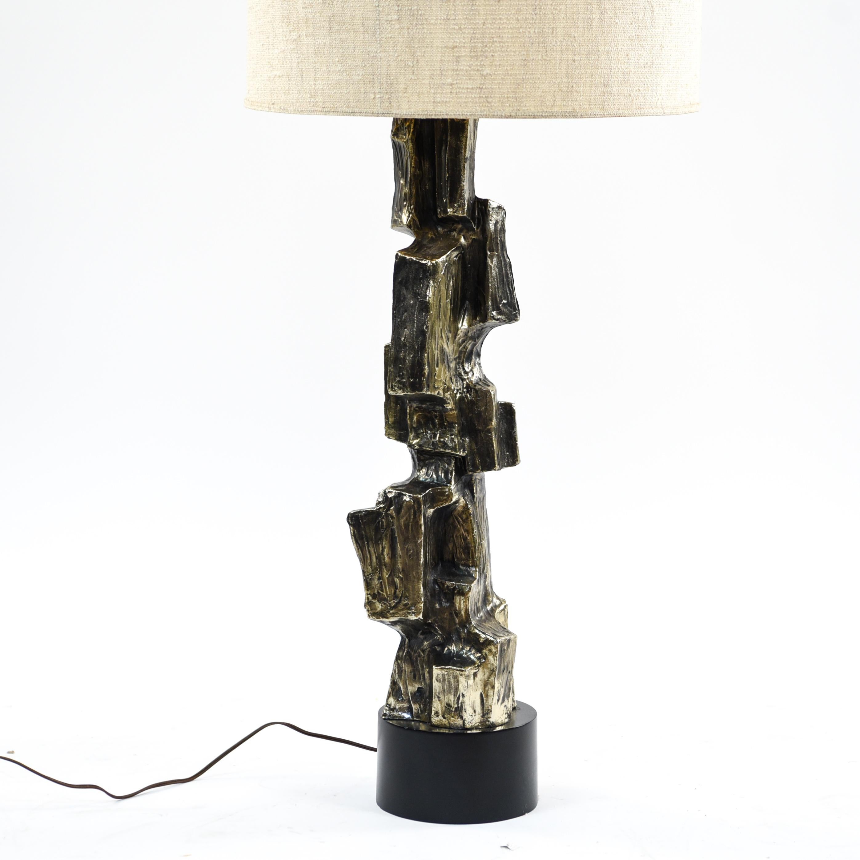 A tall sculptural metal lamp base finished in bronze patina over textural cast metal body. Manufactured by Laurel Lamp Company, 1970s. With a midcentury shade.